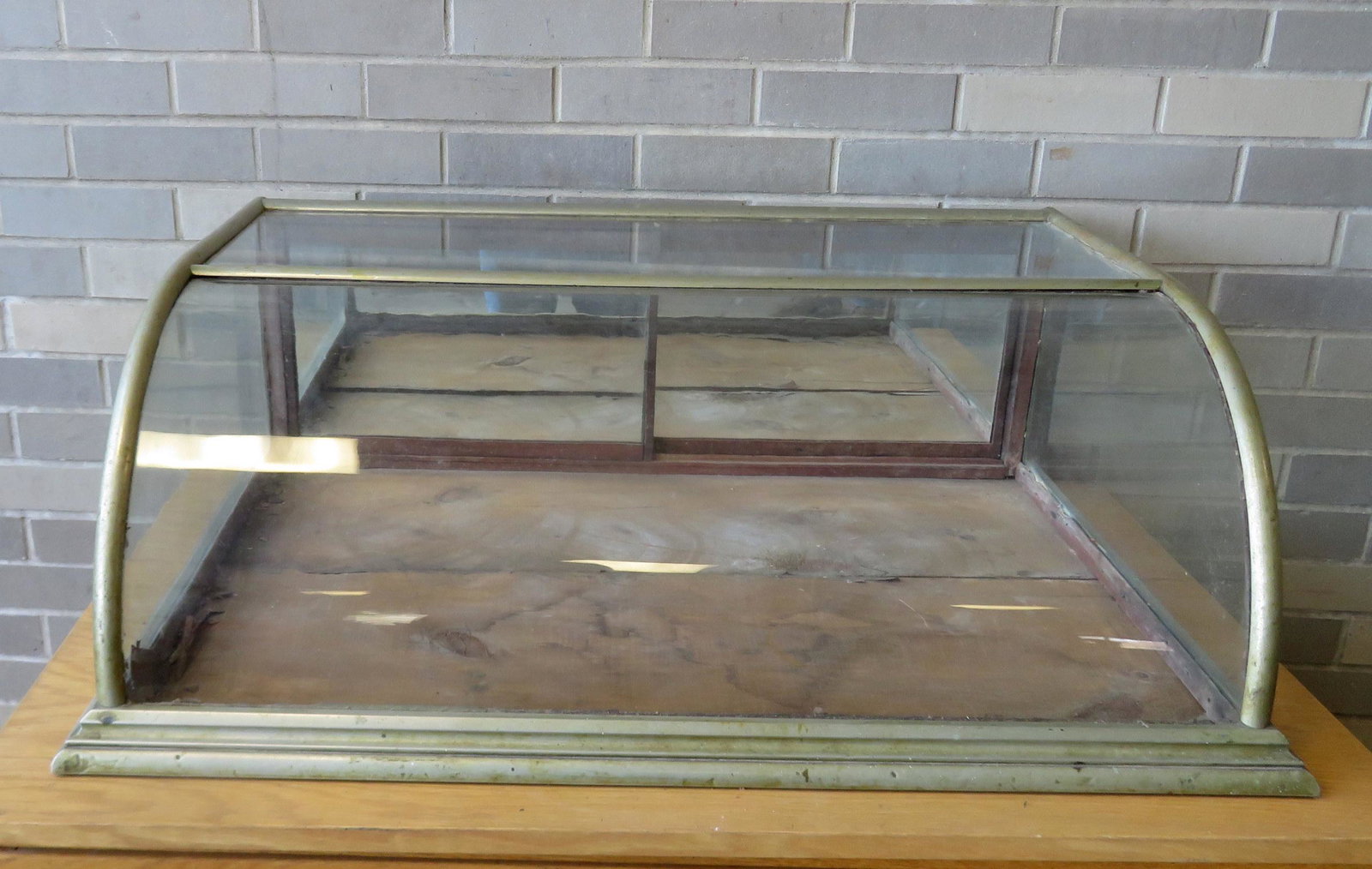 Small table top oak showcase with curved front and: Small table top oak showcase with curved front and nickel plated frame, having 2 sliding glass doors with mirror backs. 35 1/2"W x 25"D x 12"H. Condition: Use wear and dings to metal frame, otherwise 
