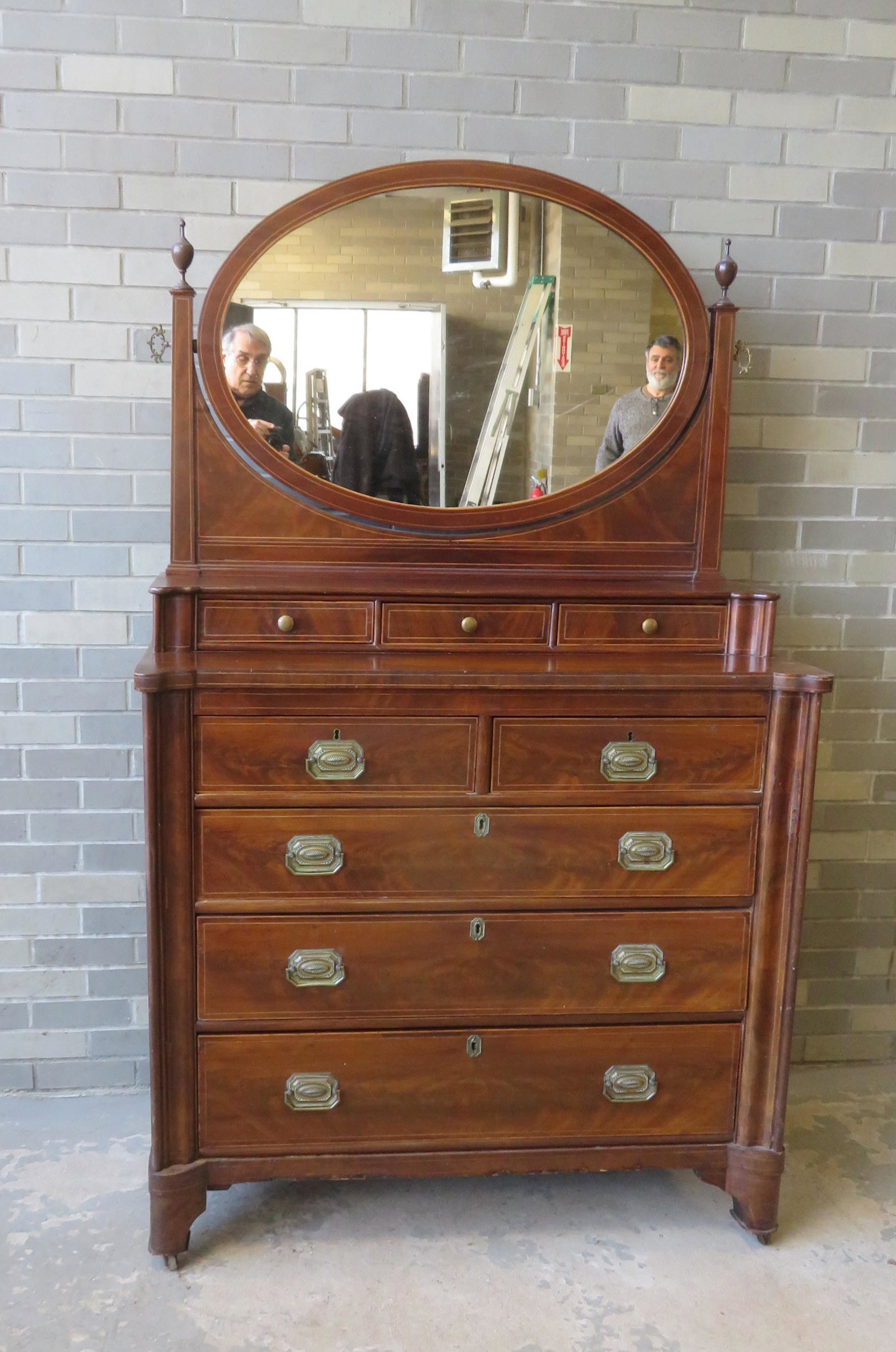 Early mahogany chest with oval mirror, extensive line: Early mahogany chest with oval mirror, extensive line inlays, having a step-back top with 3 drawers under mirror over 2 short drawers over 3 graduated drawers. Hepplewhite style pulls appear to be ori