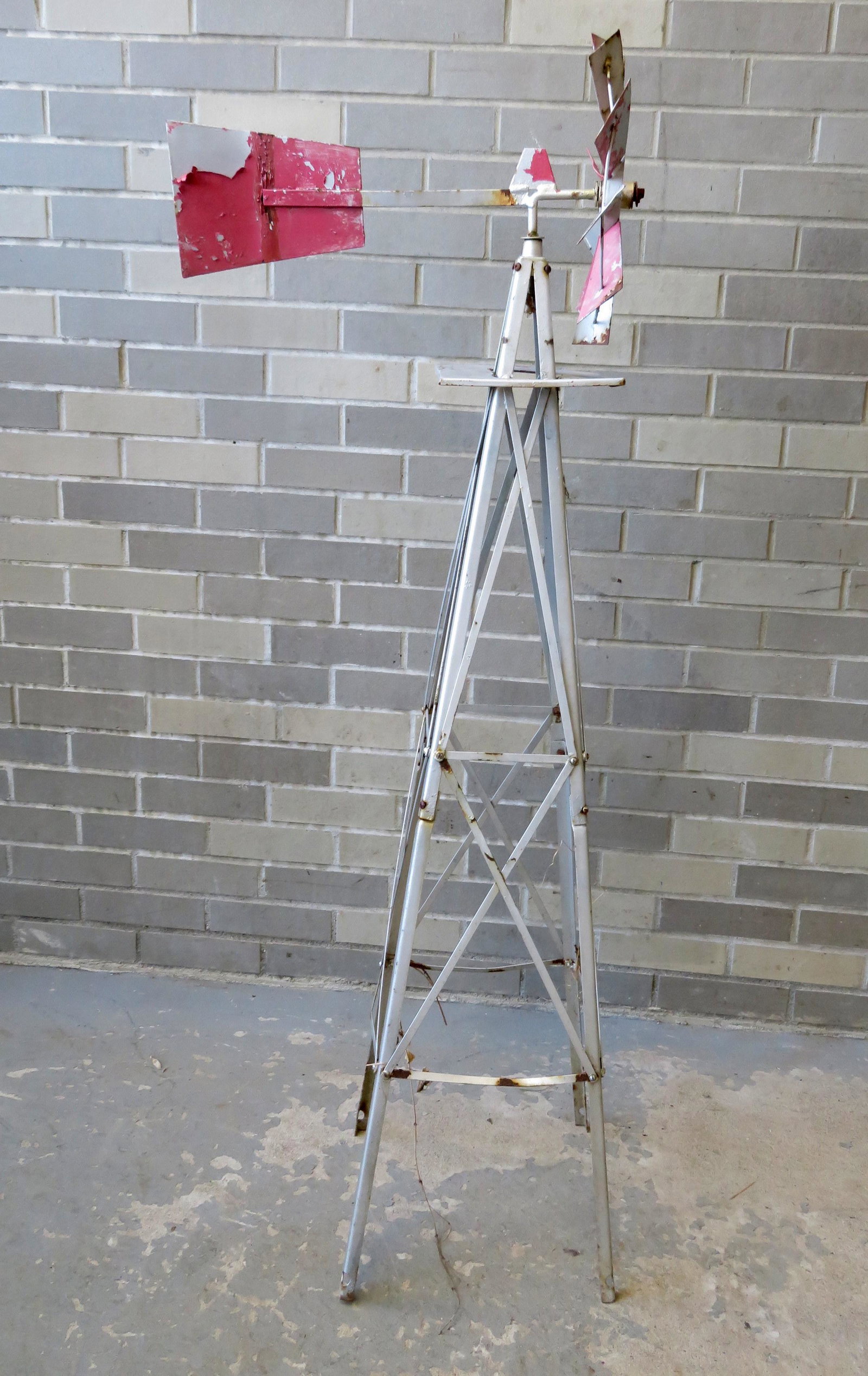 Sheet metal garden windmill on stand, good working: Sheet metal garden windmill on stand, good working condition. Traces of original paint. 51"H x 19"L (directional) x 12" square at base.