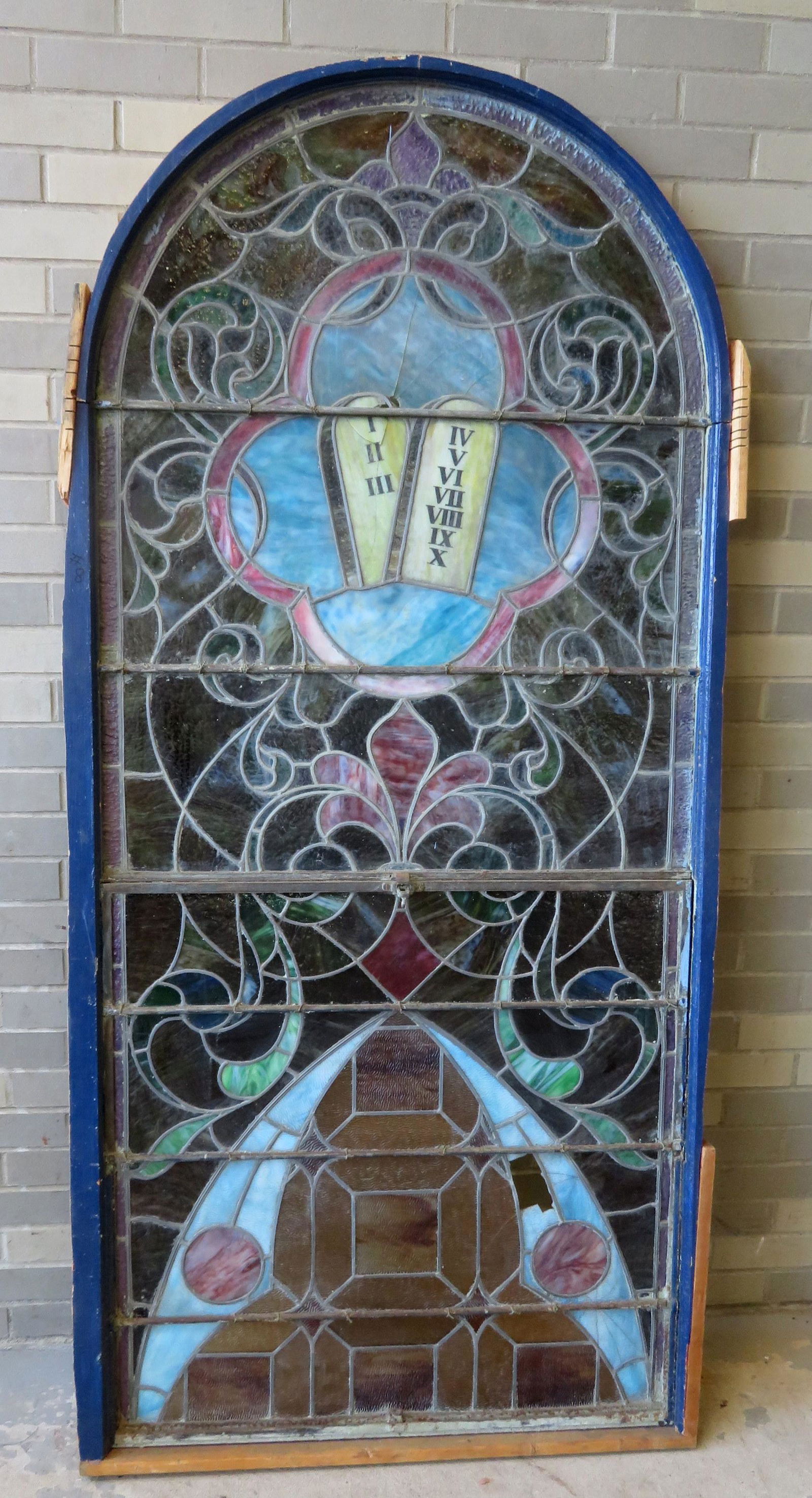 Large stained and leaded glass church window in 2: Large stained and leaded glass church window in 2 sections, opens in center, and having a domed top. The top section decorated with tablets of the Ten Commandments and the bottom section mostly with s