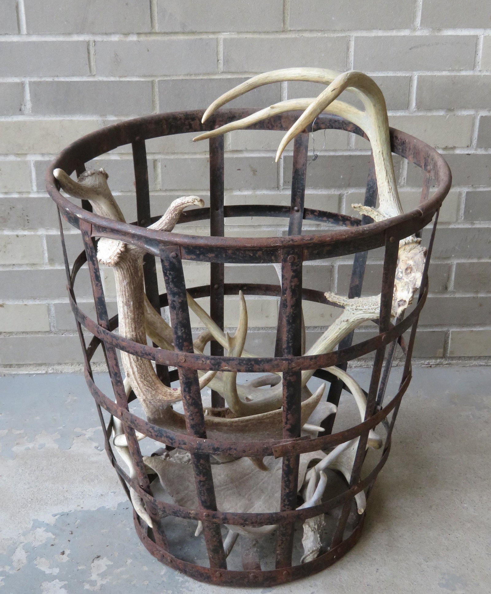 Open weave metal basket combined with 4 sets of deer: Open weave metal basket combined with 4 sets of deer antlers. The basket stands 22"H x 20 1/2"D. All in good condition.