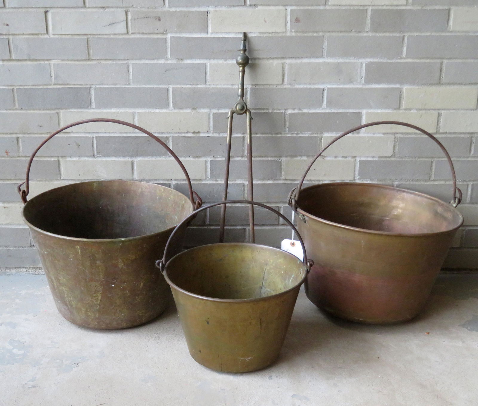 Grouping of 4 country items including: A pair of iron: Grouping of 4 country items including: A pair of iron and brass fireplace tongs, 29"L, early 19th century; and 3 brass buckets with bale handles including "The American Brass Kettle" 12 1/2"D x 9"H, t
