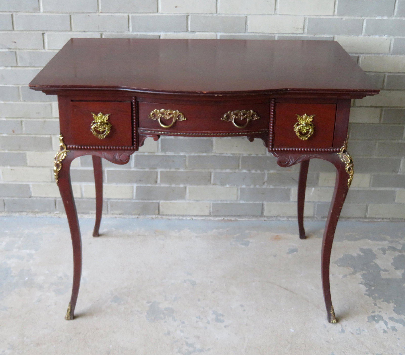 Fancy French vanity in birch wood stained mahogany,: Fancy French vanity in birch wood stained mahogany, having a shaped top over 3 drawers with ornate brass pulls and cabriole legs with applied ormolu. Carved and shaped apron. 36"W x 24"D x 30 1/2"H. S