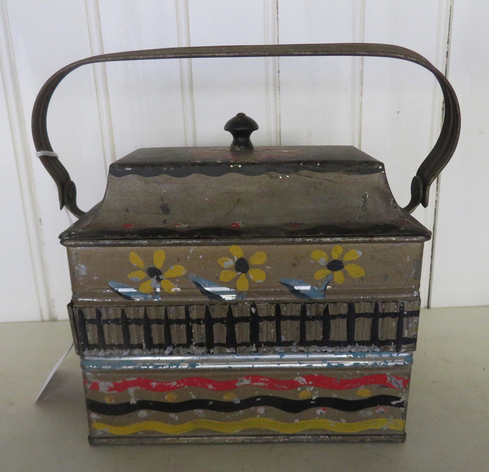 Hand painted tin lunch pail with bail handle, decorated: Hand painted tin lunch pail with bail handle, decorated with daisies behind a fence and colorful wavy lines along the base - the interior with 2 tin canisters with hand painted floral lids. Some paint