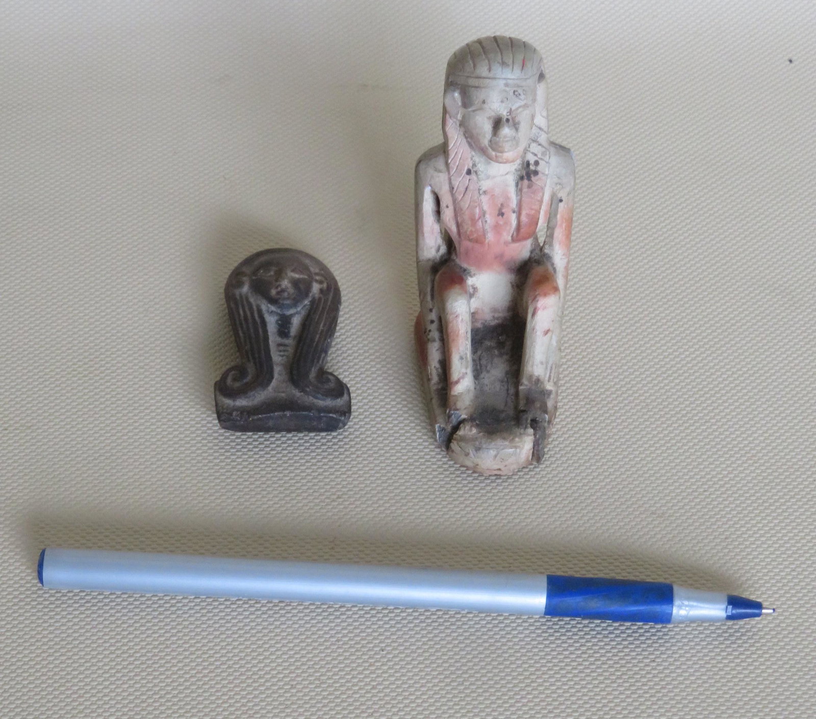 Two small carved ancient stone figures that appear to: Two small carved ancient stone figures that appear to be Egyptian Pharaohs. The first in a seated position - 3"H x 2"W - repair to the front foot area which has a glue repair, and the second in a dark
