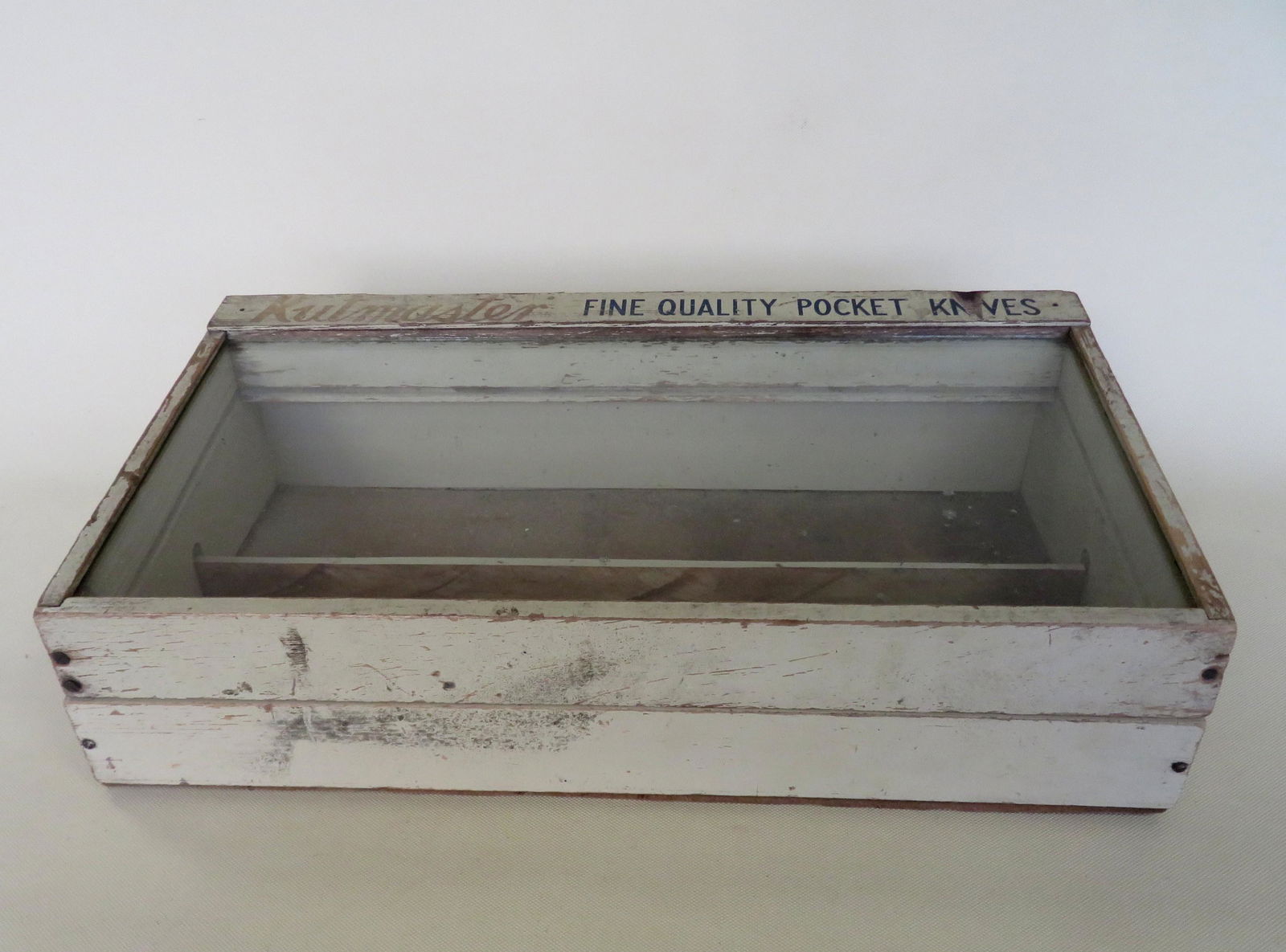 Small Kutmaster pocket knife showcase with lift top in: Small Kutmaster pocket knife showcase with lift top in original gold and blue lettering on putty ground. Sectioned interior. Use wear, but overall good condition. 1`9 3/4"W x 10 3/4"D x 5 1/2"H.