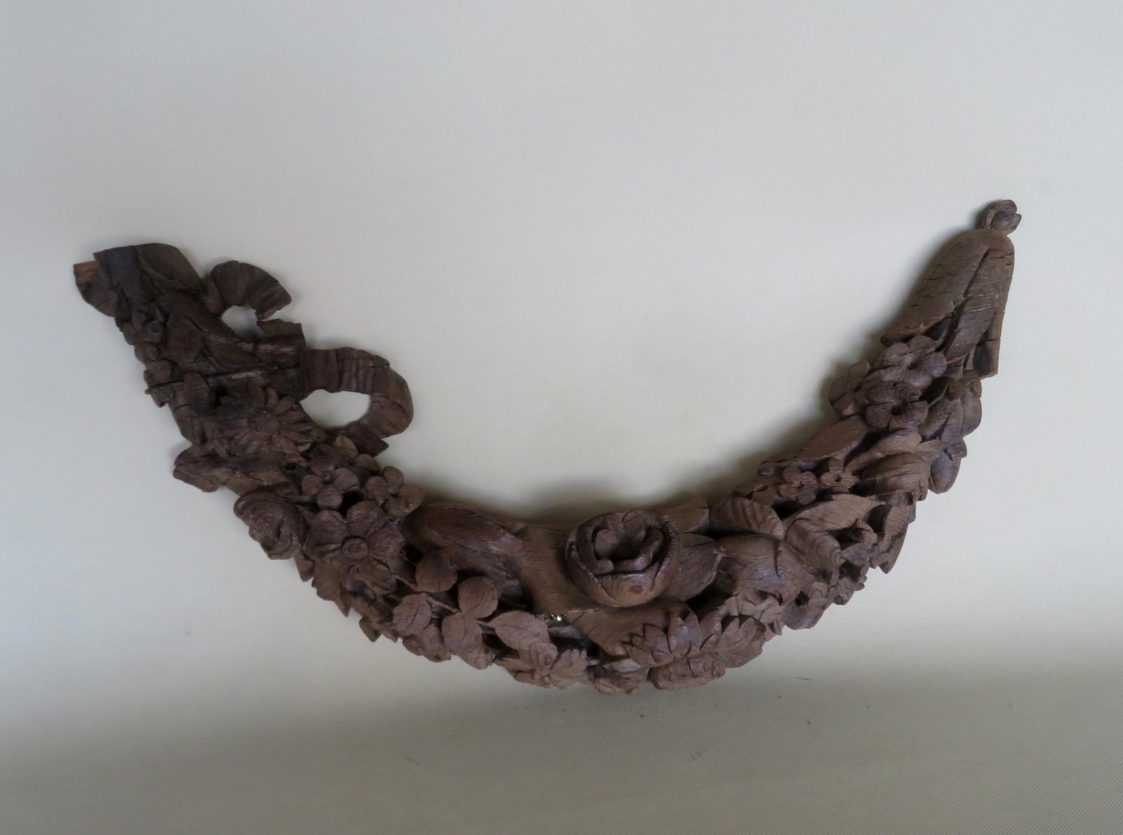 Carved wooden wreath decorated with flowers, loss to: Carved wooden wreath decorated with flowers, loss to one end, very detailed crisp carving, typical age checks, and overall good condition. 22 3/4"W x 13"H x 3 1/2" deep. 19th century.