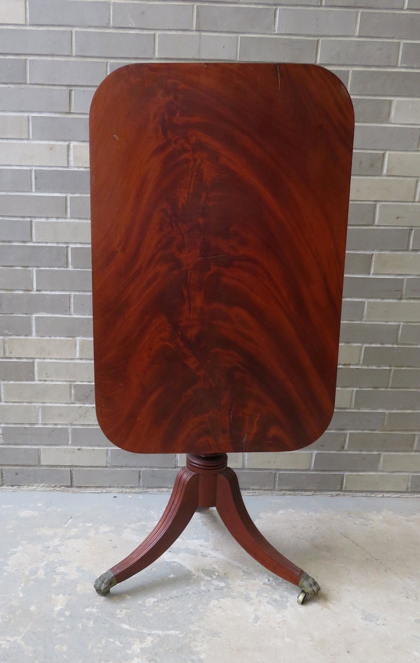 Late Sheraton tilt-top candlestand with beautiful Cuban: Late Sheraton tilt-top candlestand with beautiful Cuban mahogany top over turned pedestal leading to 3 fluted legs with brass feet, circa 1830-40. Very good condition. 31" x 20 1/2" (top) x 27 1/2"H.