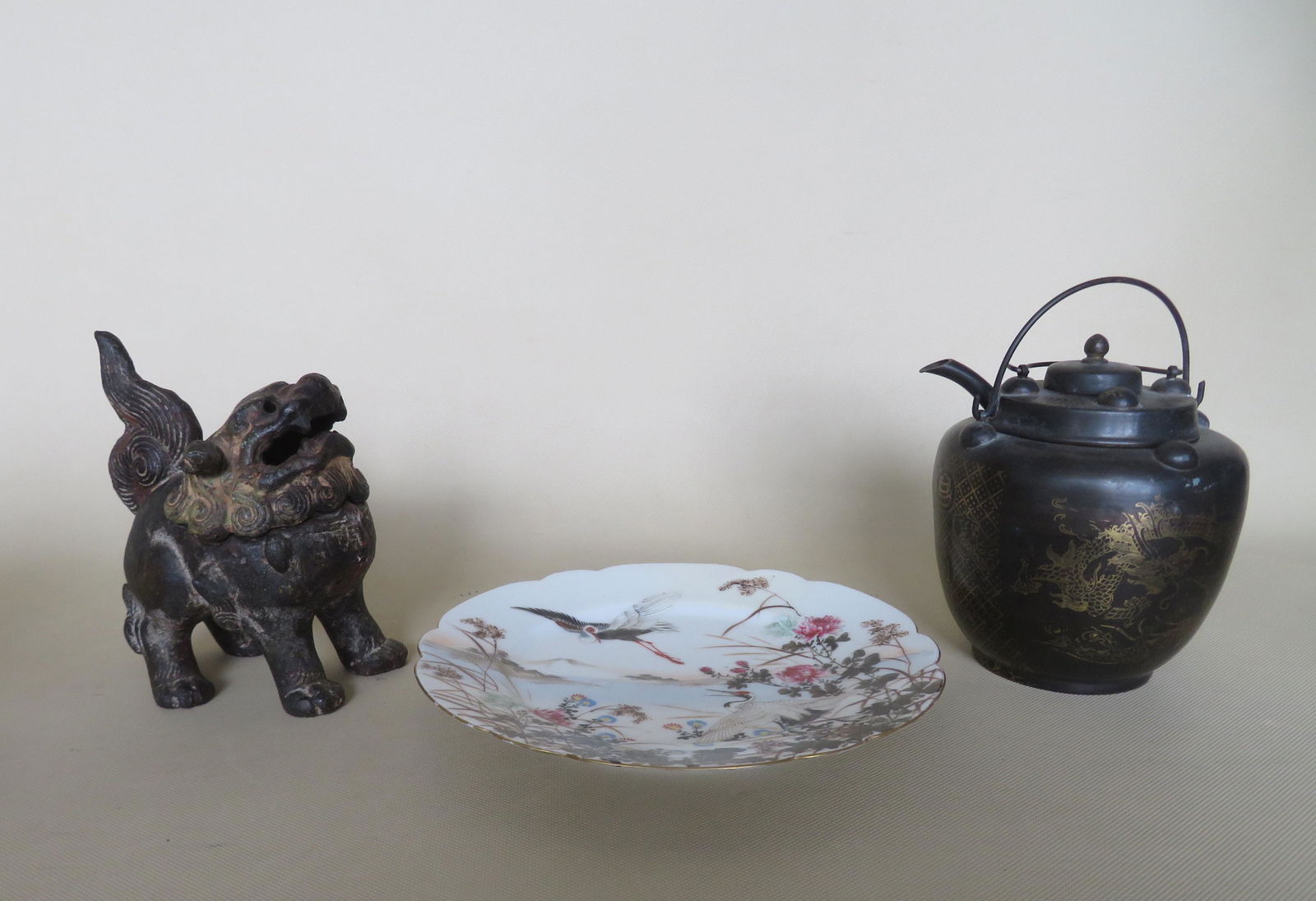 Three oriental decorative objects including a hand: Three oriental decorative objects including a hand painted plated depicting 2 cranes in landscape setting - original signature on base - scalloped edge - very good condition - 8 1/2"D; a japanned tin