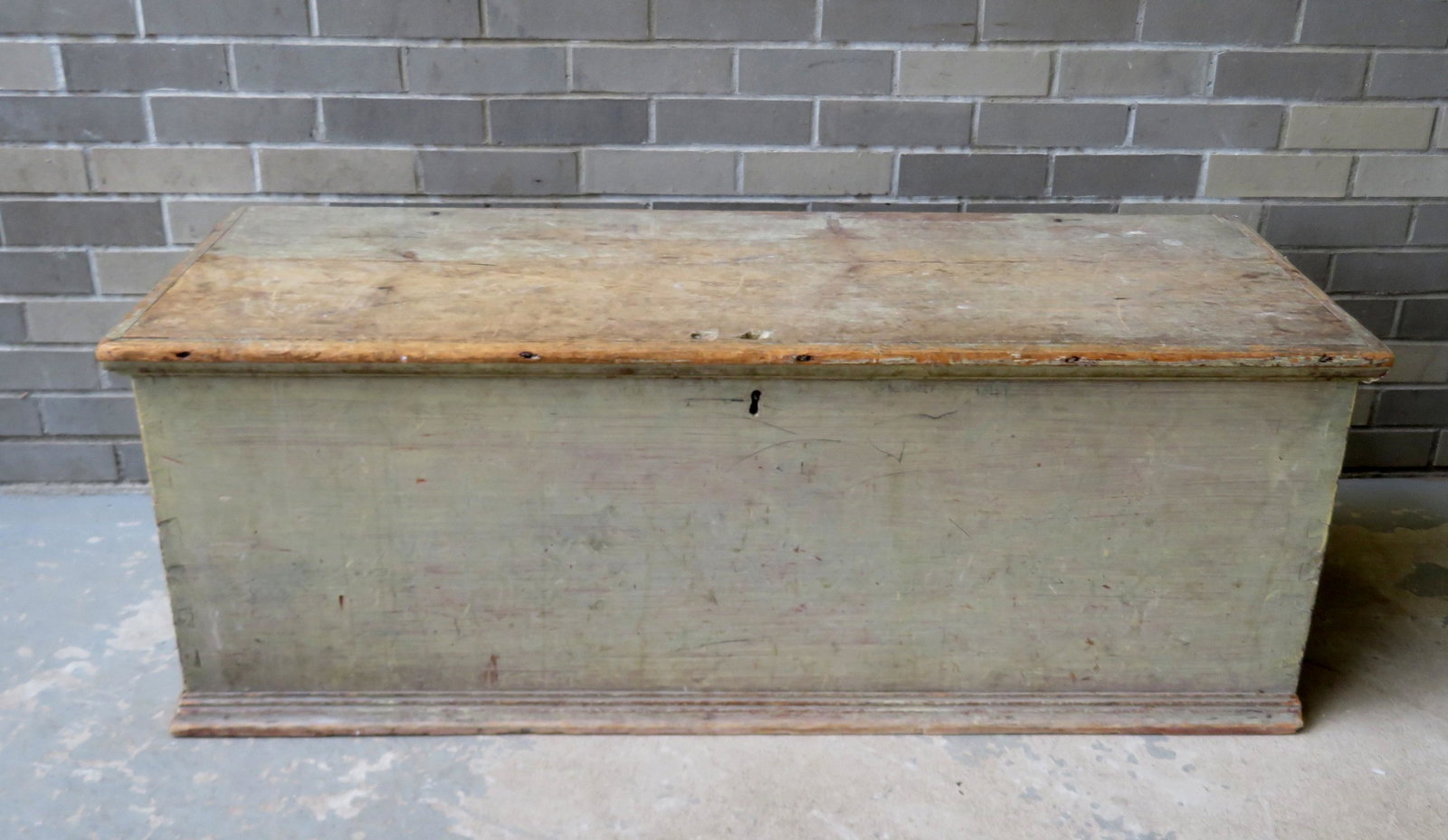 An 18th century blanket box in a light green paint with: An 18th century blanket box in a light green paint with rattail hinges, and molded base. Condition - the paint is worn on the top, one piece of base molding missing from right side, but overall good c