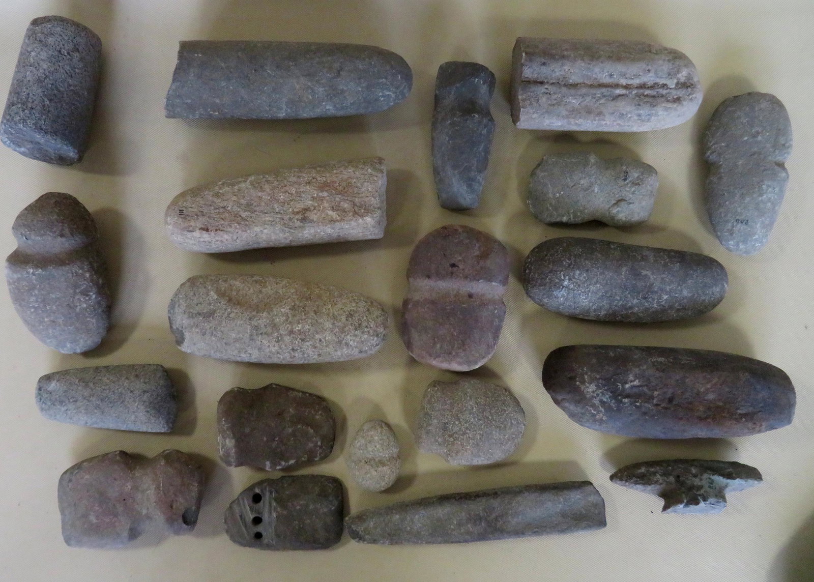 Grouping of 20 Native American stone artifacts: Grouping of 20 Native American stone artifacts including pestles and axe heads, some with losses. The largest 8"L.