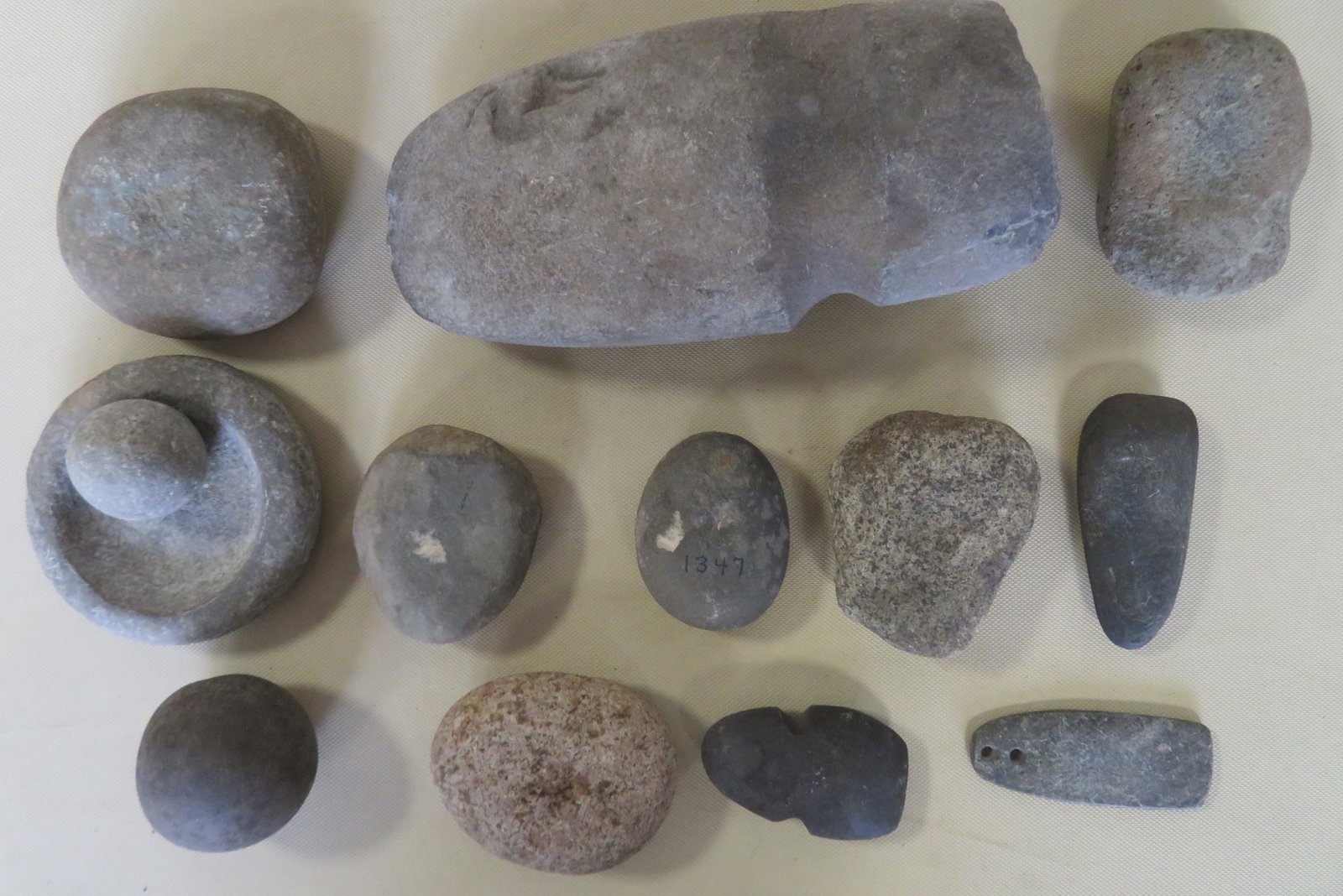 Grouping of 13 Native American stone artifacts: Grouping of 13 Native American stone artifacts including a large axe head - 10"L x 4 1/2"W x 2 3/4" thick, a small mortar and pestle, fire starters, etc.