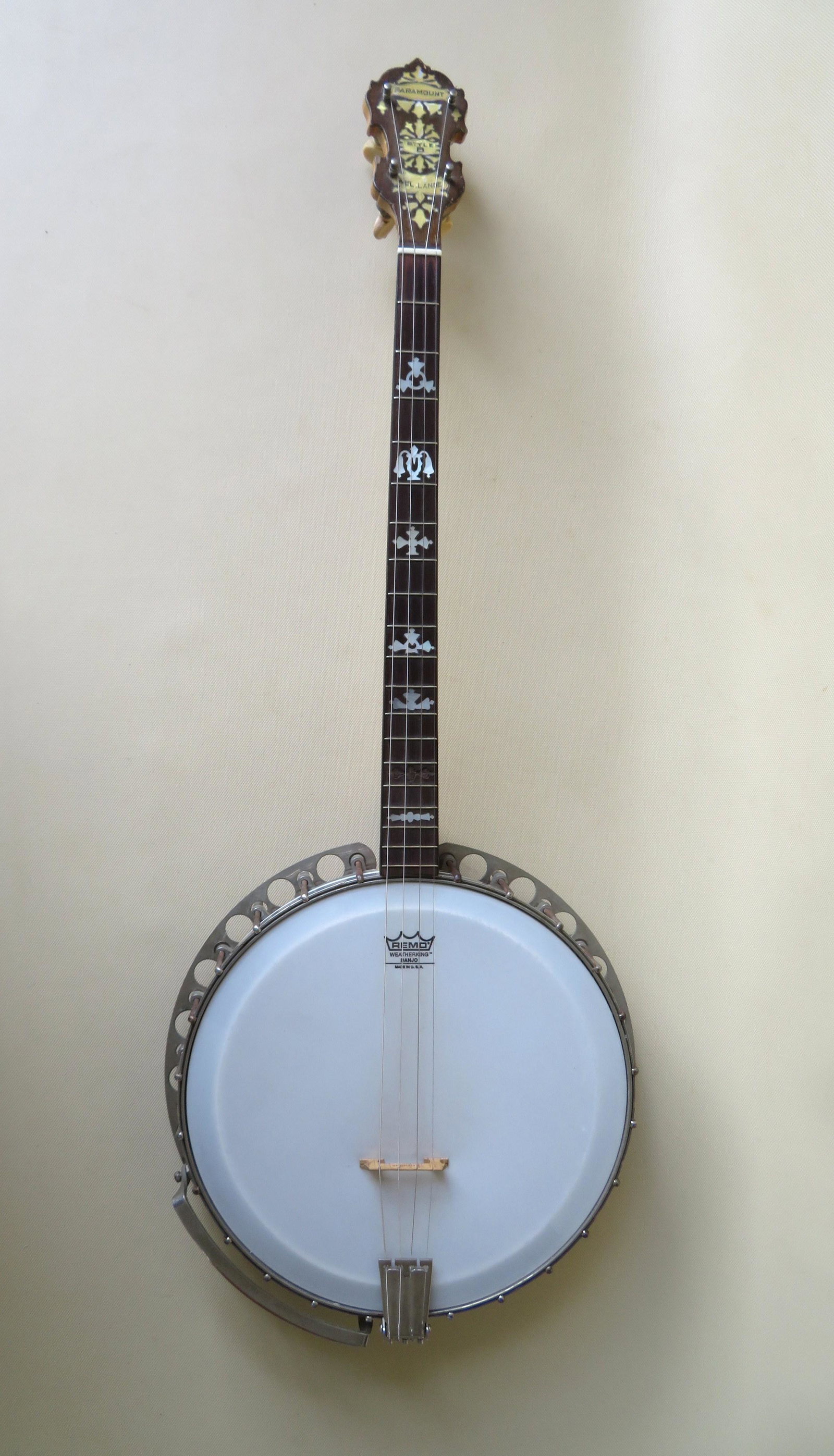 Vintage wooden banjo signed "Paramount Style B / Wm. L.: Vintage wooden banjo signed "Paramount Style B / Wm. L. Lange" on mother of pearl decorated headstock with 4 strings, maple wood frame, rosewood fret board with mother of pearl inlay (1 piece on inlay