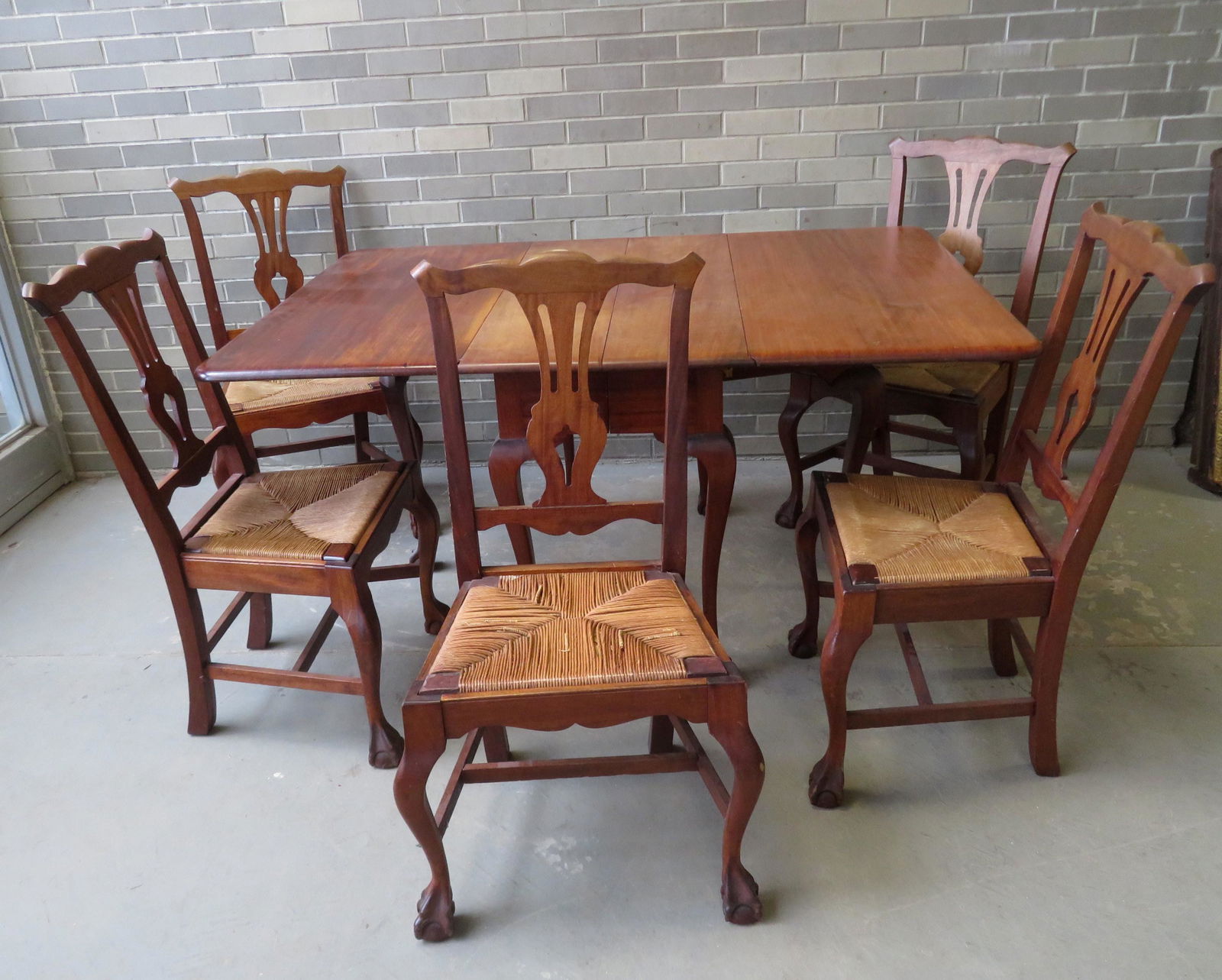 Chippendale style mahogany dining room set consisting: Chippendale style mahogany dining room set consisting of a drop-leaf table with claw and ball feet, and 5 Chippendale style chairs with claw and ball seat and having rope-rush seats (one seat with los