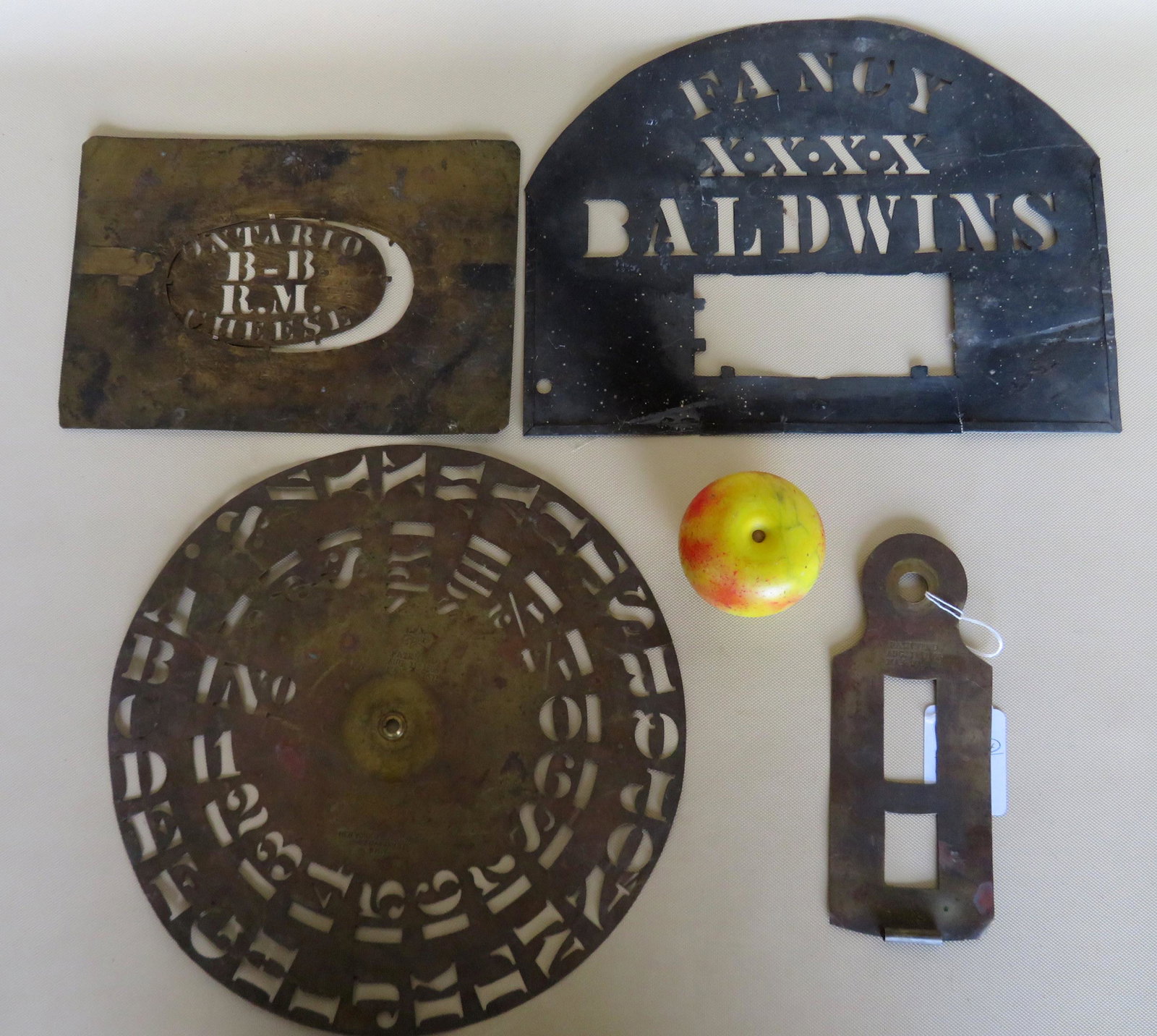Grouping of 4 brass stencils including "FANCY: Grouping of 4 brass stencils including "FANCY BALDWINS", calendar missing dials signed NY Stencil Works pat. 1871, a lock shaped hinged stencil Pat 1871, and "ONTARIO CHEESE". The largest 13"D. Most i