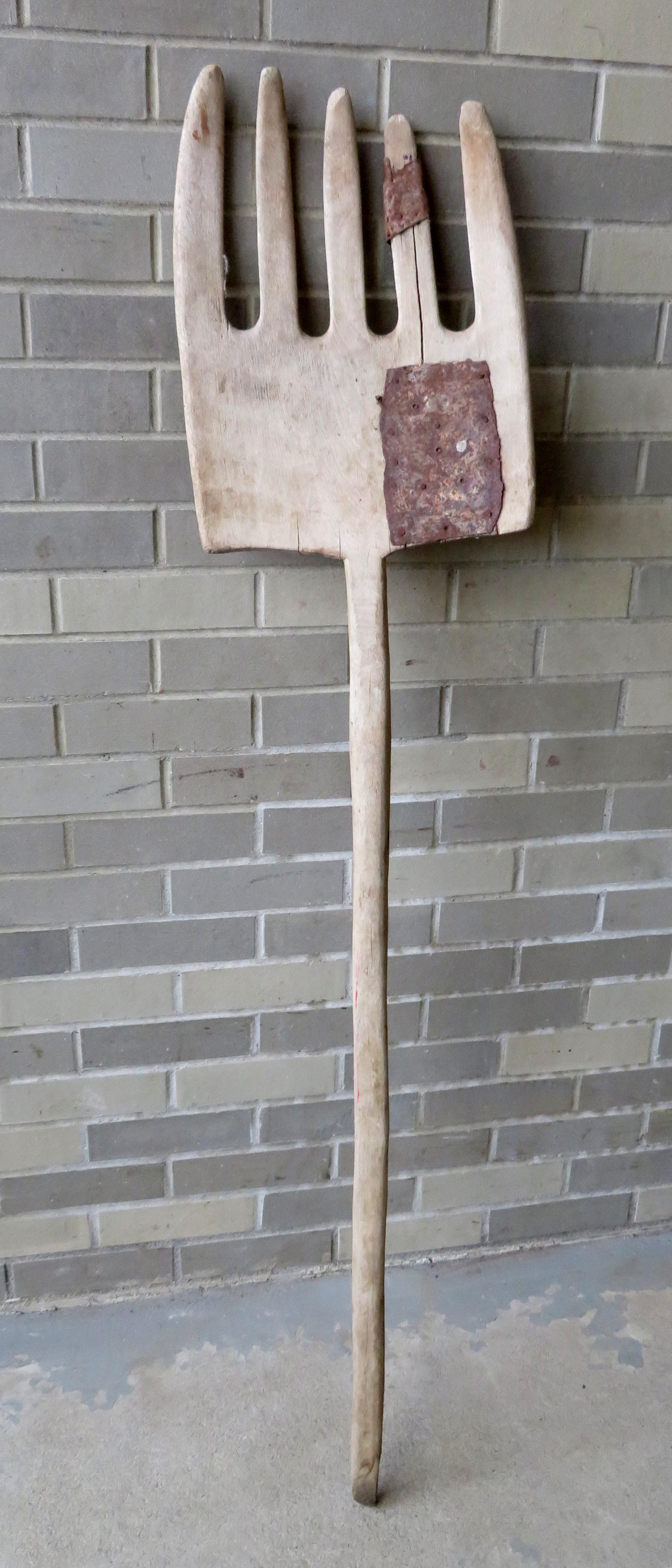 Primitive wooden hay fork with old tin repair, early to: Primitive wooden hay fork with old tin repair, early to mid 19th century. 57"L x 12"W.