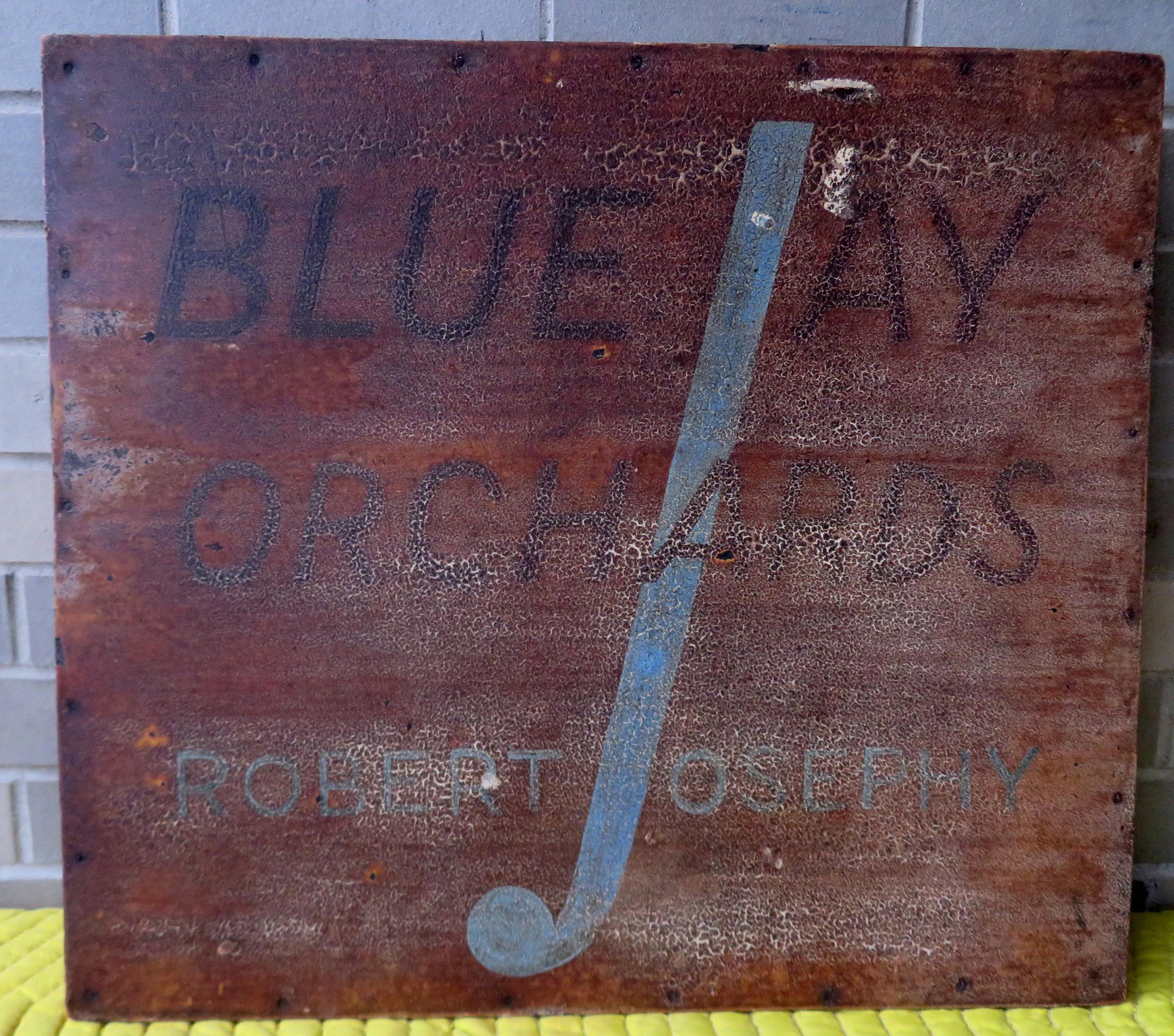 A hand painted masonite sign in original paint, marked: A hand painted masonite sign in original paint, marked "BLUE JAY / ORCHARDS / ROBERT JOSEPHY", circa 1934-1950. Paint with crazing and separation, and while the sign is all original, it is in fair con