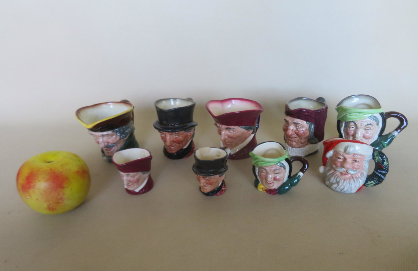 Grouping of 9 miniature Royal Doultan toby mugs: Grouping of 9 miniature Royal Doultan toby mugs including 2 "The Cardinal", 2 "Sairey Gamp", "Santa Claus", "Dick Turpin", others with no names. One of the small mugs with a large rim chip, others in 