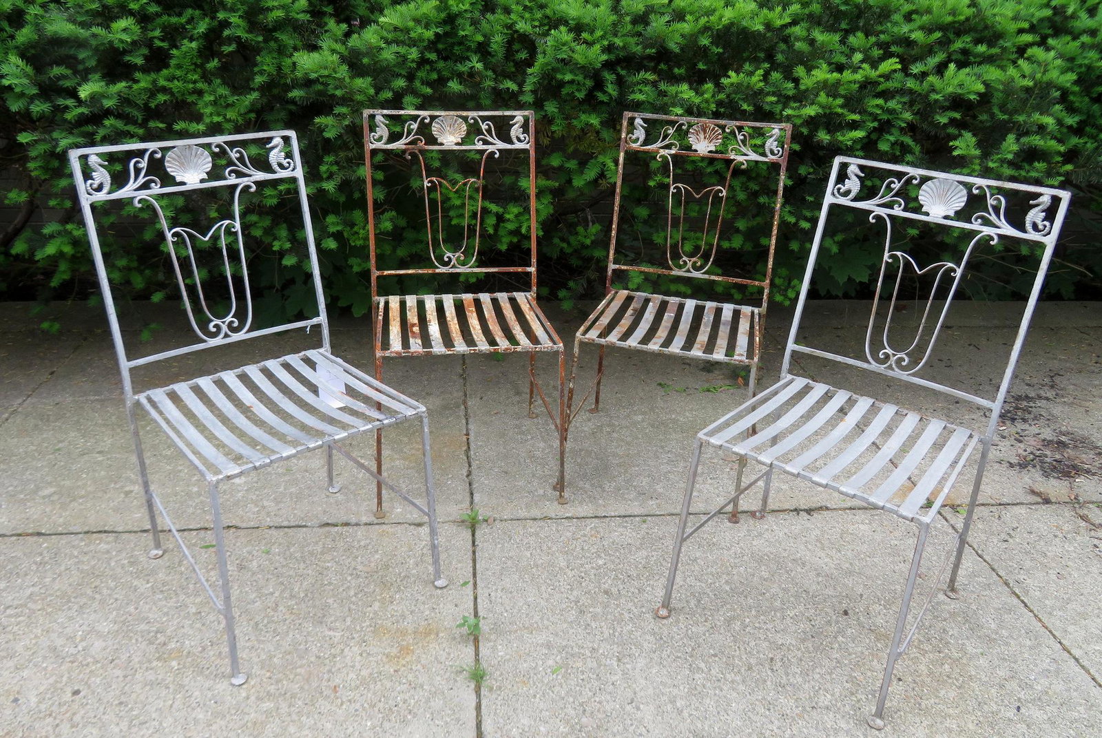 Set of 4 matching iron patio chairs with sheet iron: Set of 4 matching iron patio chairs with sheet iron slats in seat and the back decorated with seahorses, scrolls and seashell. Minor surface rust and wear, and overall good condition, early to mid 20t