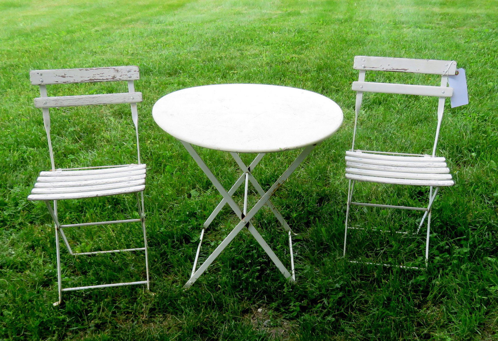 Small child size folding French cafÃ© table with 2: Small child size folding French cafÃ© table with 2 chairs, 20th century, in old white paint - slight rusting in joints, but overall good condition. Table size 22 1/2"dia. X 26 3/4"H.