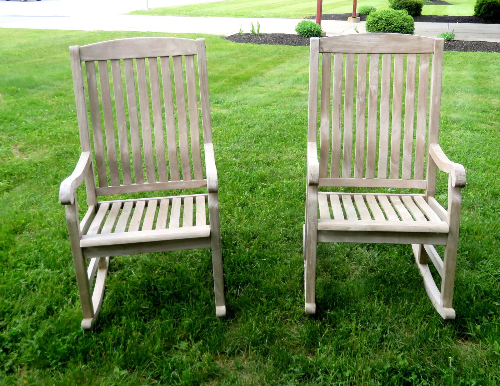 Two teak wood porch rockers in good condition, late: Two teak wood porch rockers. Weathered but in good condition, late 20th century. 25 1/4"W x 31 1/4"D x 46"H.