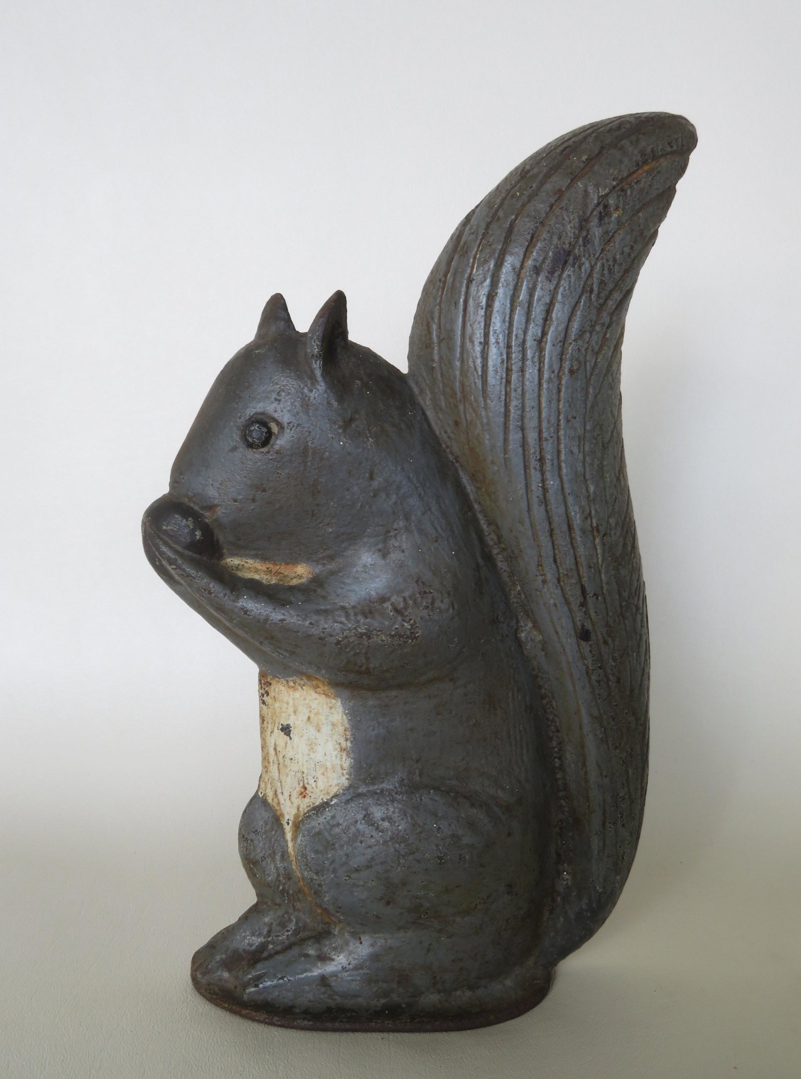 Cast iron door stop in the form of a seated squirrel: Cast iron door stop in the form of a seated squirrel eating nut, paint appears to be all original, early 20th century. Slight wear, and overall very good condition. 10 1/2"H x 6 1/4"W. Nice form but u