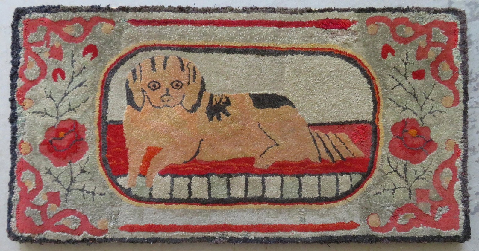 Mounted hooked rug depicting a Spaniel dog resting on: Mounted hooked rug depicting a Spaniel dog resting on rug surrounded by flowers, late 19th century. 36 1/2" x 18 1/2". Some small areas may have been professionally repaired, but unable to confirm sin
