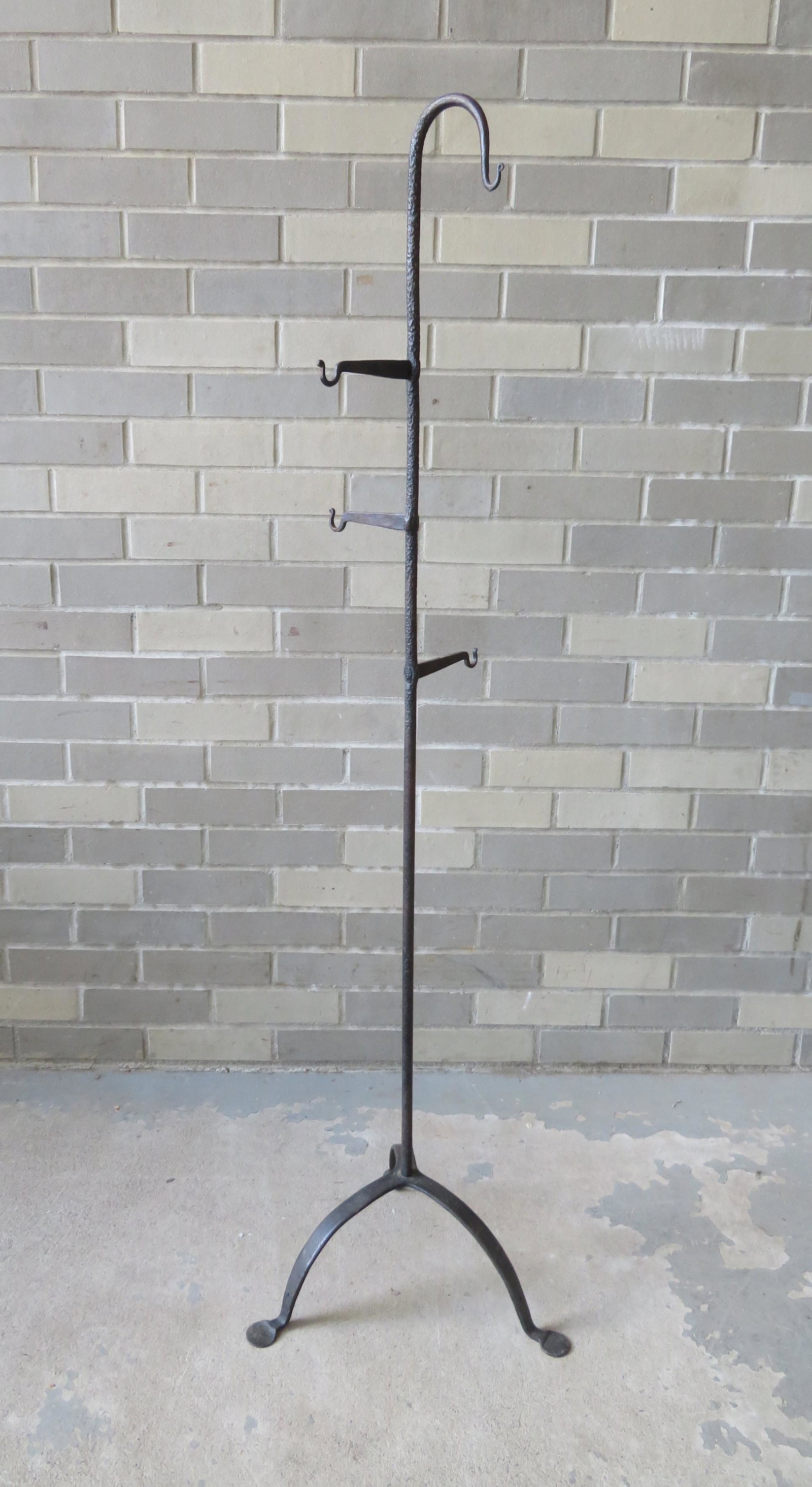 A Queen Ann hand forged iron lighting device holder,: A Queen Ann hand forged iron lighting device holder, 18th century, with 3 hangers mortised through the central post which attaches to a tripod base with small circular feet, very good condition. 51 3/