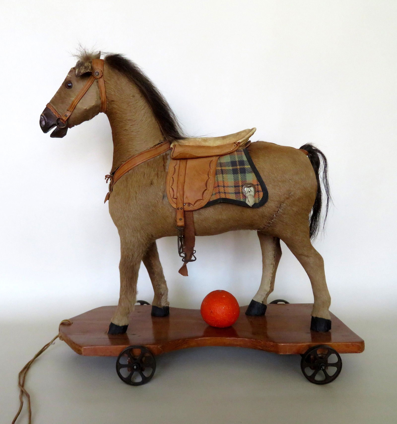 Large wooden horse pull toy constructed of carved wood: Large wooden horse pull toy constructed of carved wood with real animal hair/hide sewn around the body and applied to the mane, and tail which appear to be original. The horse with original leather sa