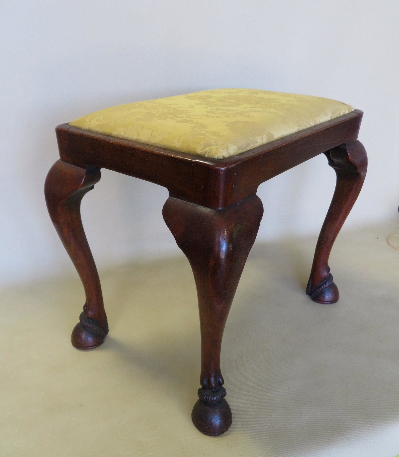 A very fine mahogany Queen Ann style (2nd period, late: A very fine mahogany Queen Ann style (2nd period, late 19th century), upholstered vanity stool with hand carved horse hoof feet. With impressed mark of maker "J.S.". Very good condition. Size 21 1/2"L