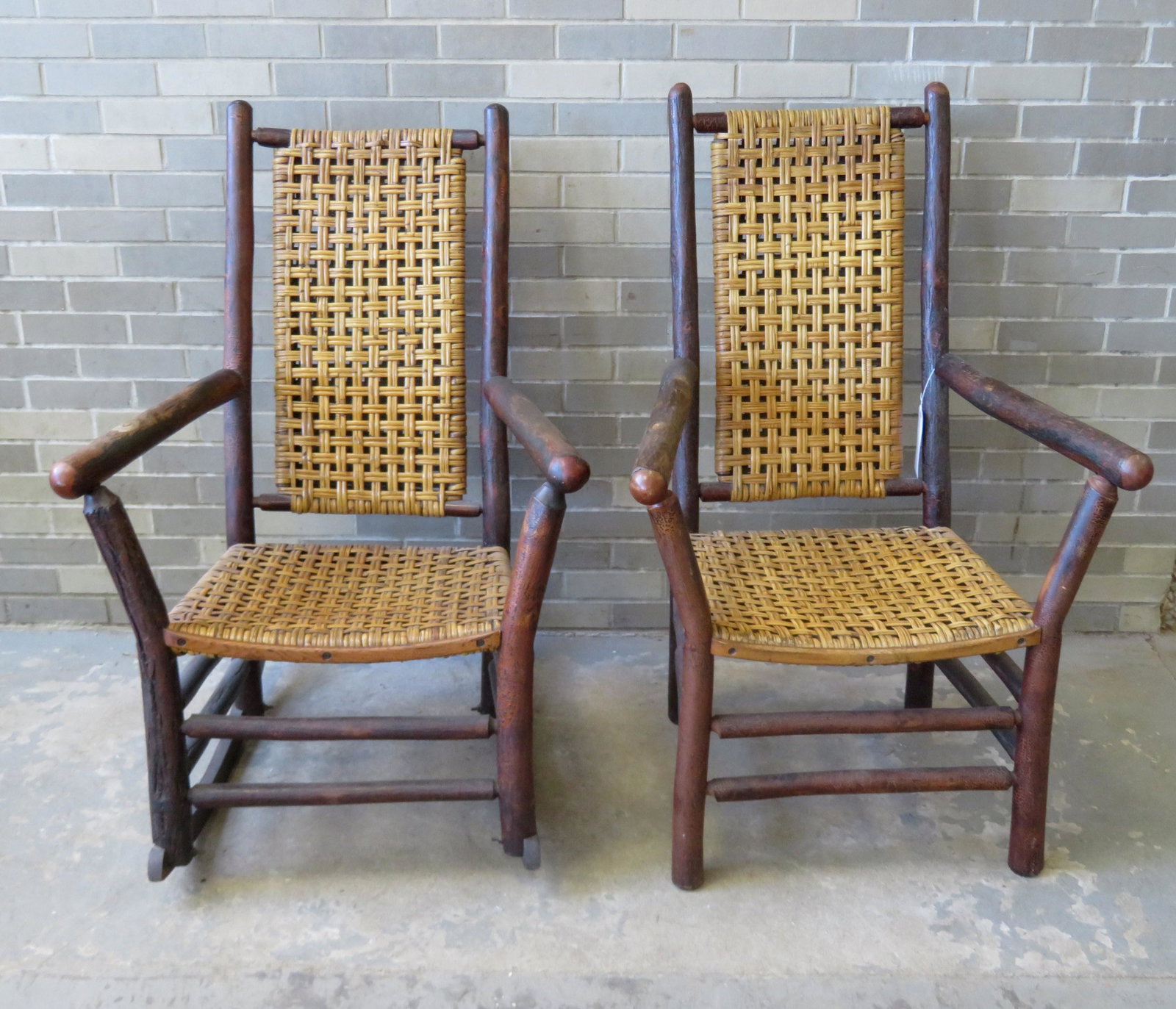 Two exceptional pieces of oversized "Old Hickory": Two exceptional pieces of oversized "Old Hickory" furniture including an arm chair and matching rocker in original finish and original woven seat and back. Each with an applied circular metal "Bruce" 