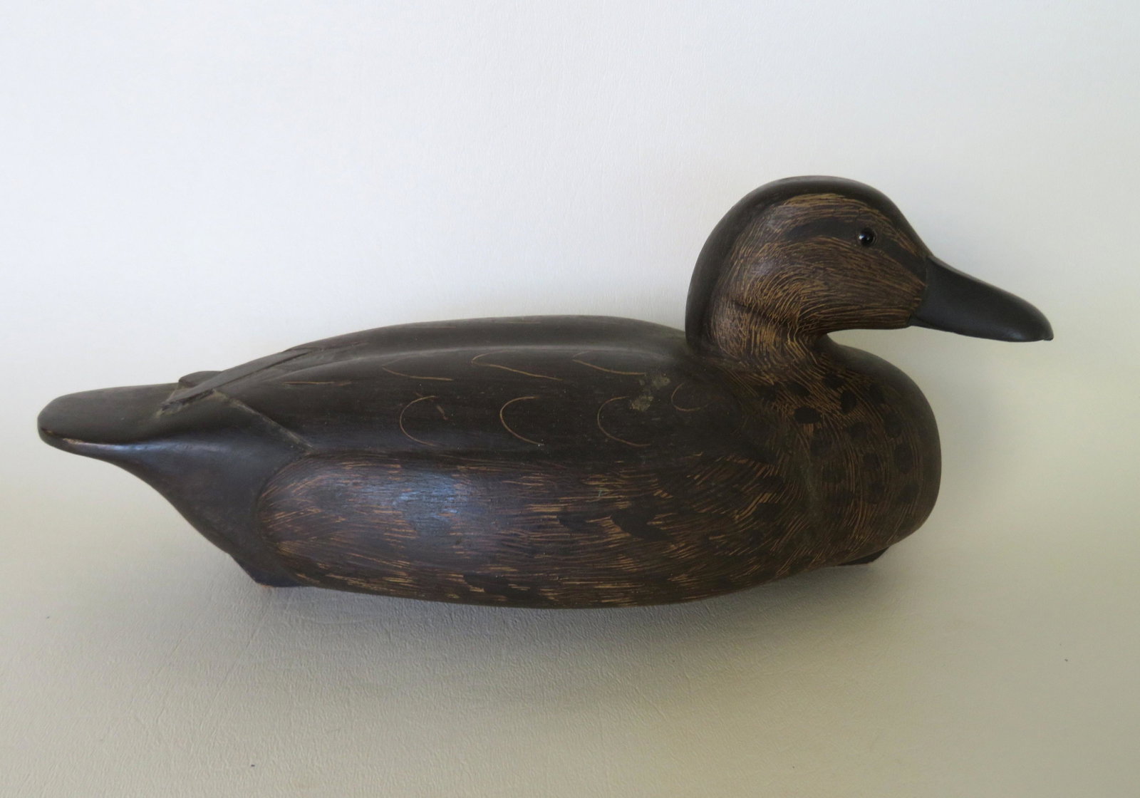 A good half size carved black duck decoy in scratched: A good half size carved black duck decoy in scratched paint, glass eyes, detailed beak and crossed wing tip, with an impressed mark on base that appears to read "RU". Very good condition. 11"L x 4 1/2