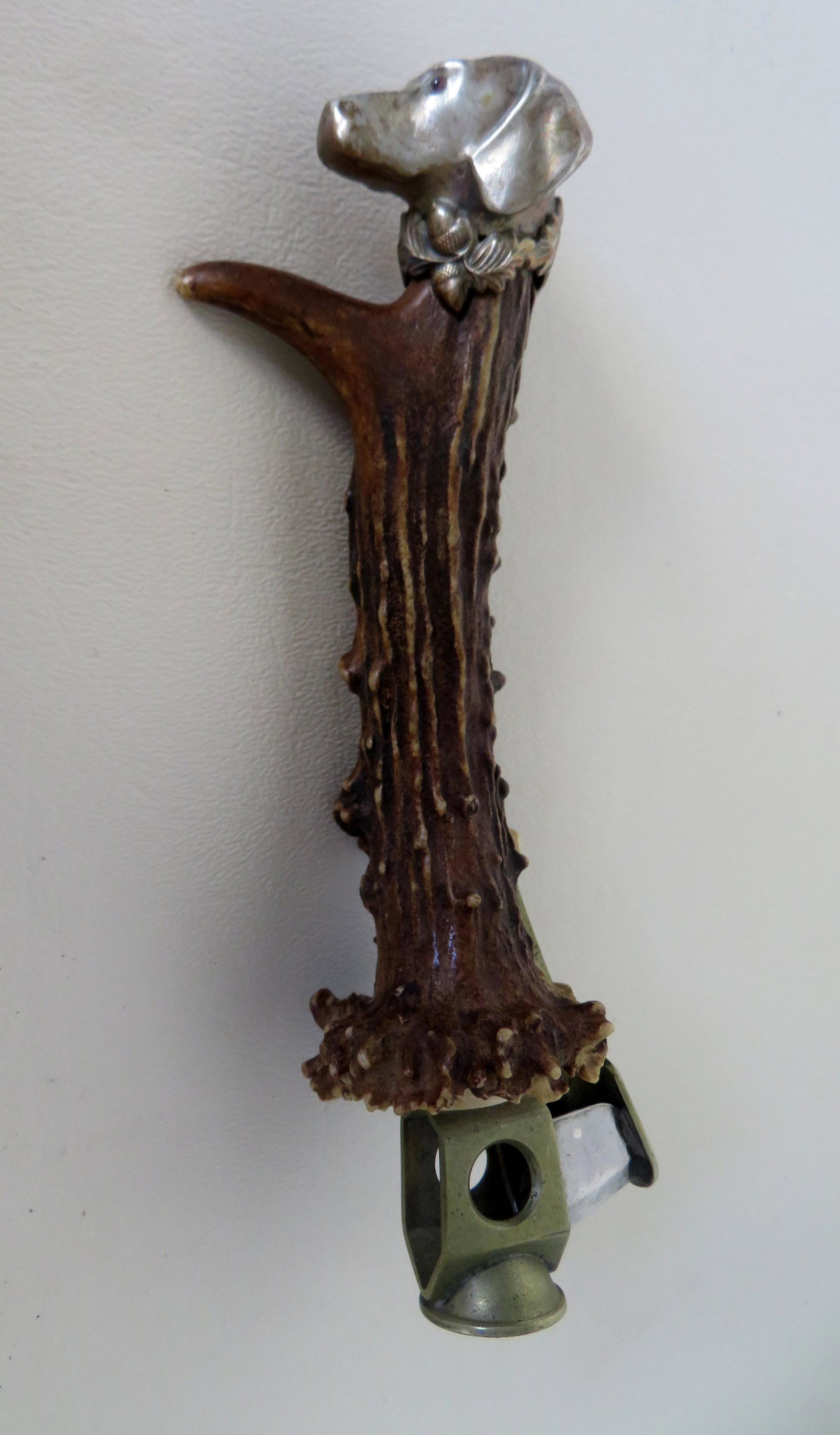 A cigar cutter having a figural silver finial of a: A cigar cutter having a figural silver finial of a Dachshund's dog head with either jeweled or glass eyes, over a horn handle. Late 19th to early 20th century. Very good condition. 6 1/2"L.