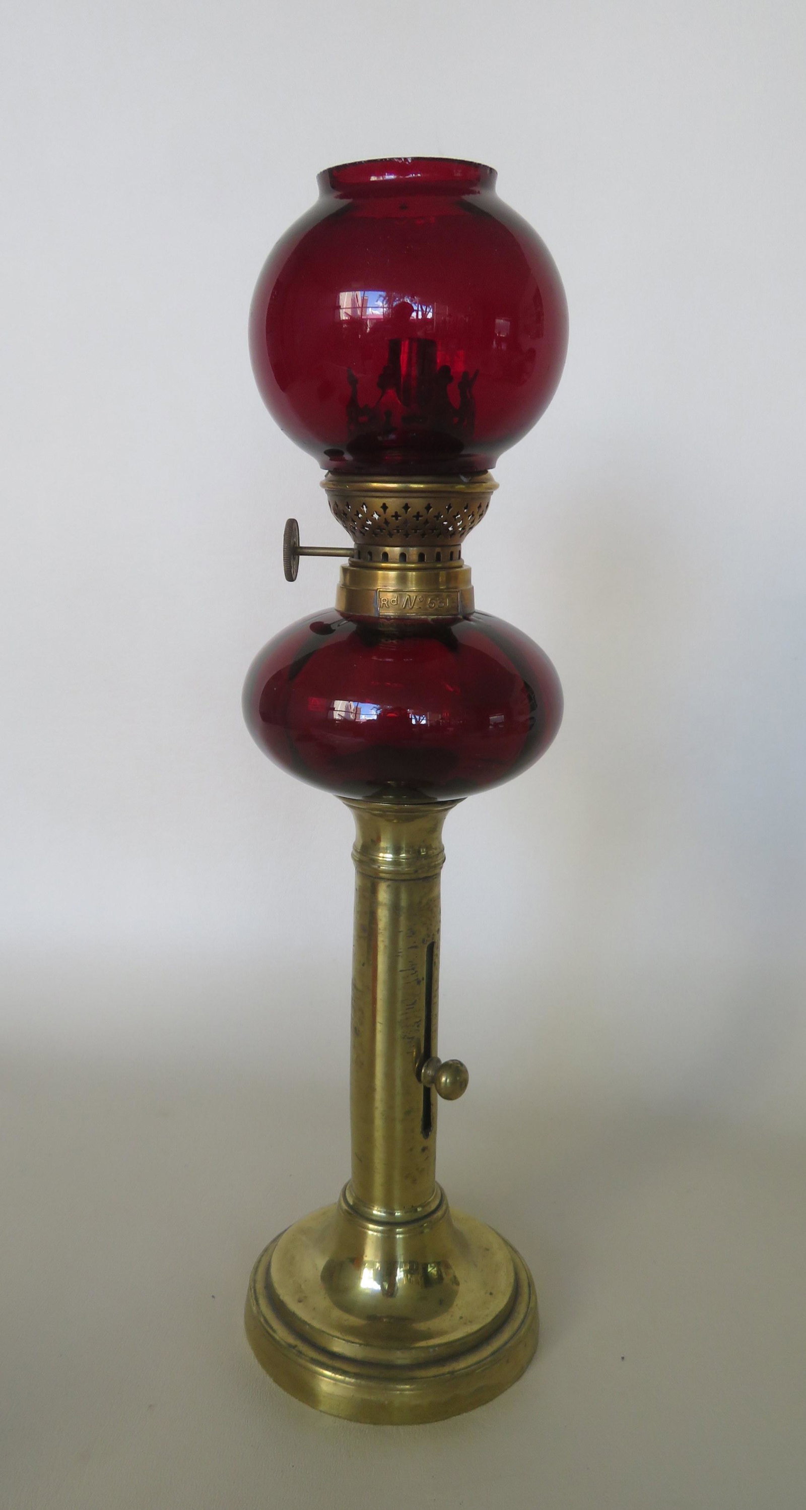 An early cranberry peg lamp with matching shade, with: An early cranberry peg lamp with matching shade, with embossed registry number on collar marked "Rd. No. 5313" - marked on the wick adjustment "Patent Reform - Kosmos - Brenner", circa 1870, and mount