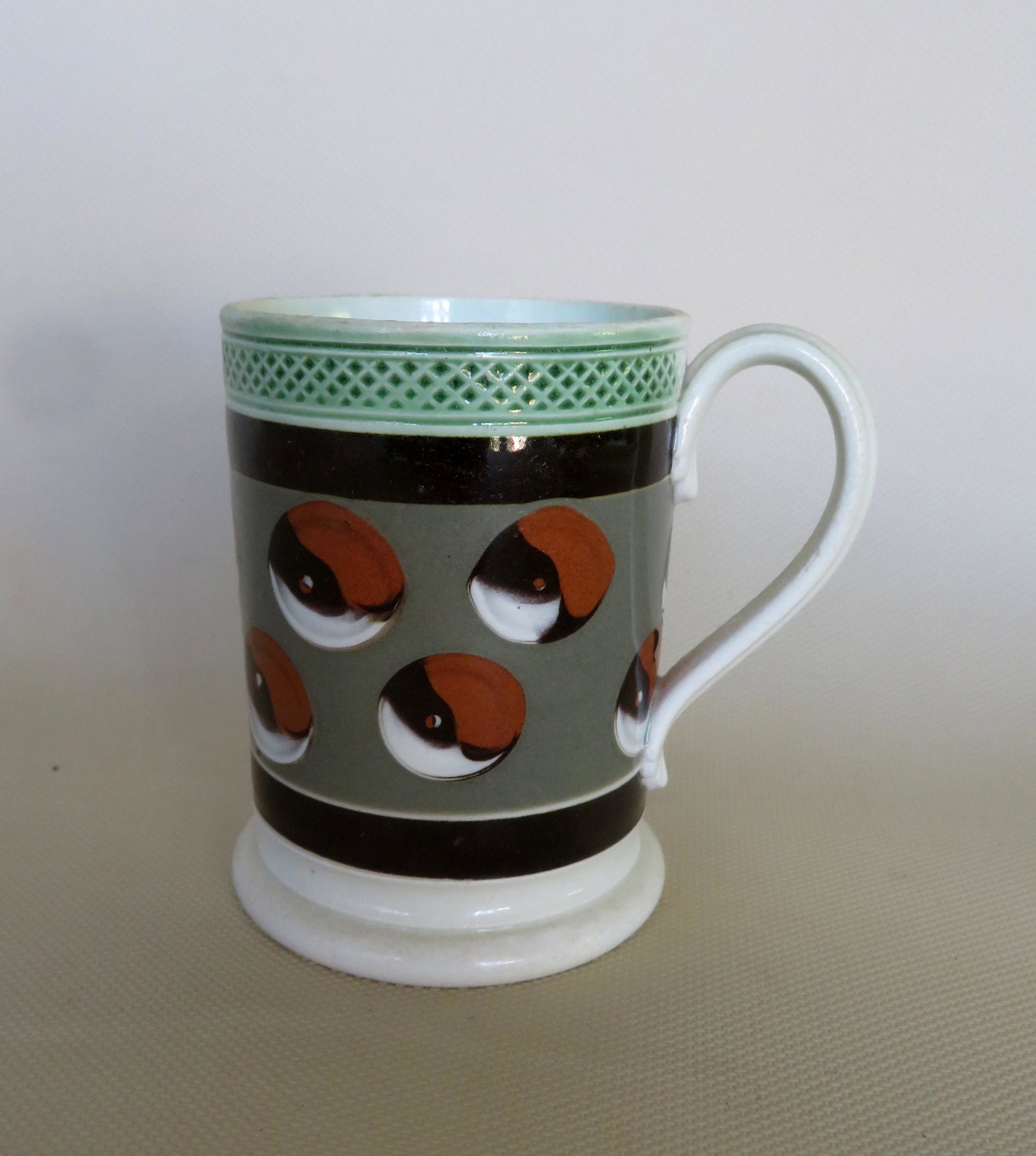 Colorful mocha child's mug in cat's eye pattern with: Colorful mocha child's mug in cat's eye pattern with applied molded leaf handle, 19th century - a small glazing imperfection on side, otherwise very good condition, no damage. 3 3/8"H. Provenance: Fro