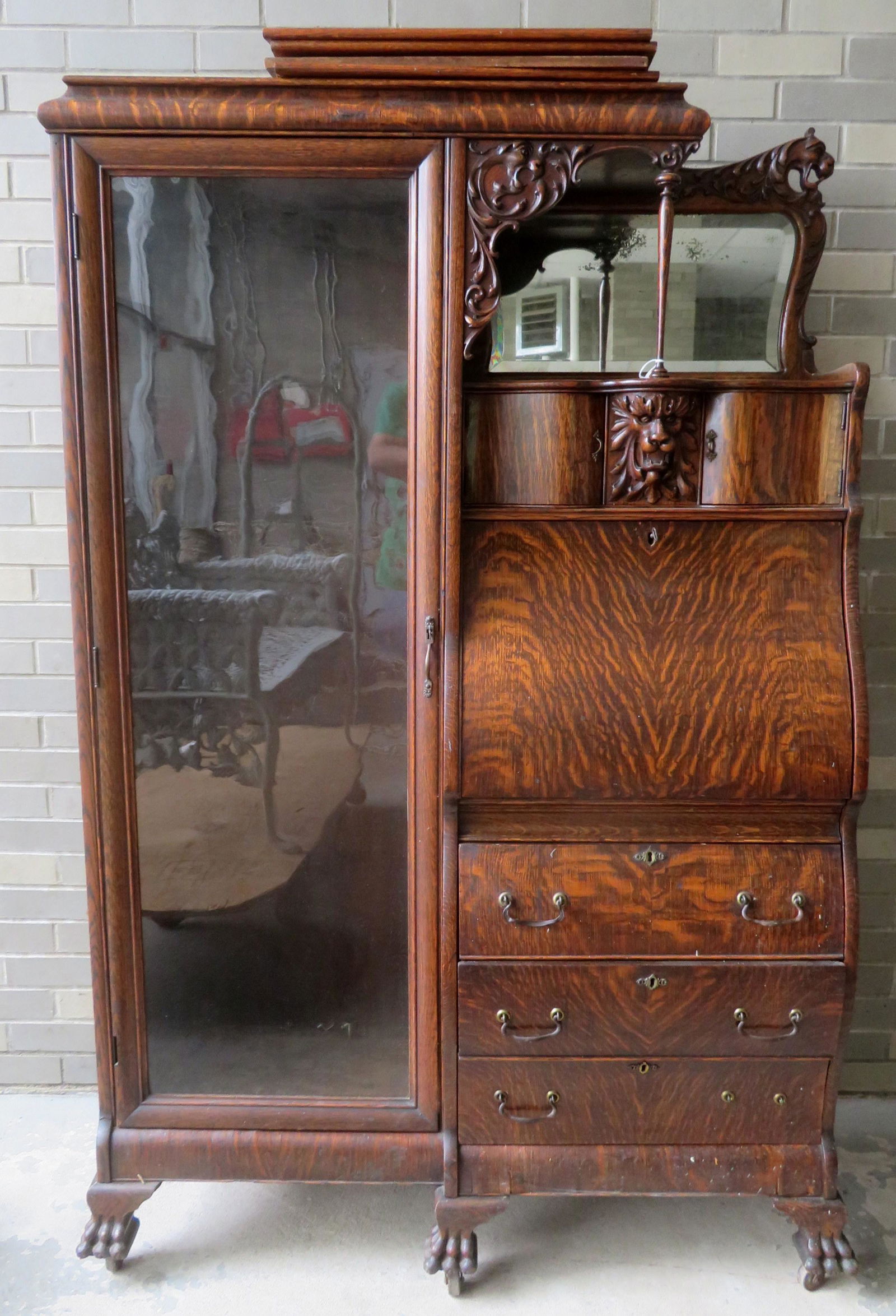 The best figured oak side-by-side desk/bookcase. The: The best figured oak side-by-side desk/bookcase. The unit with a glass front bookcase on the left and a top shelf with beveled glass mirror and 2 applied griffin carvings, over 2 serpentine horizontal