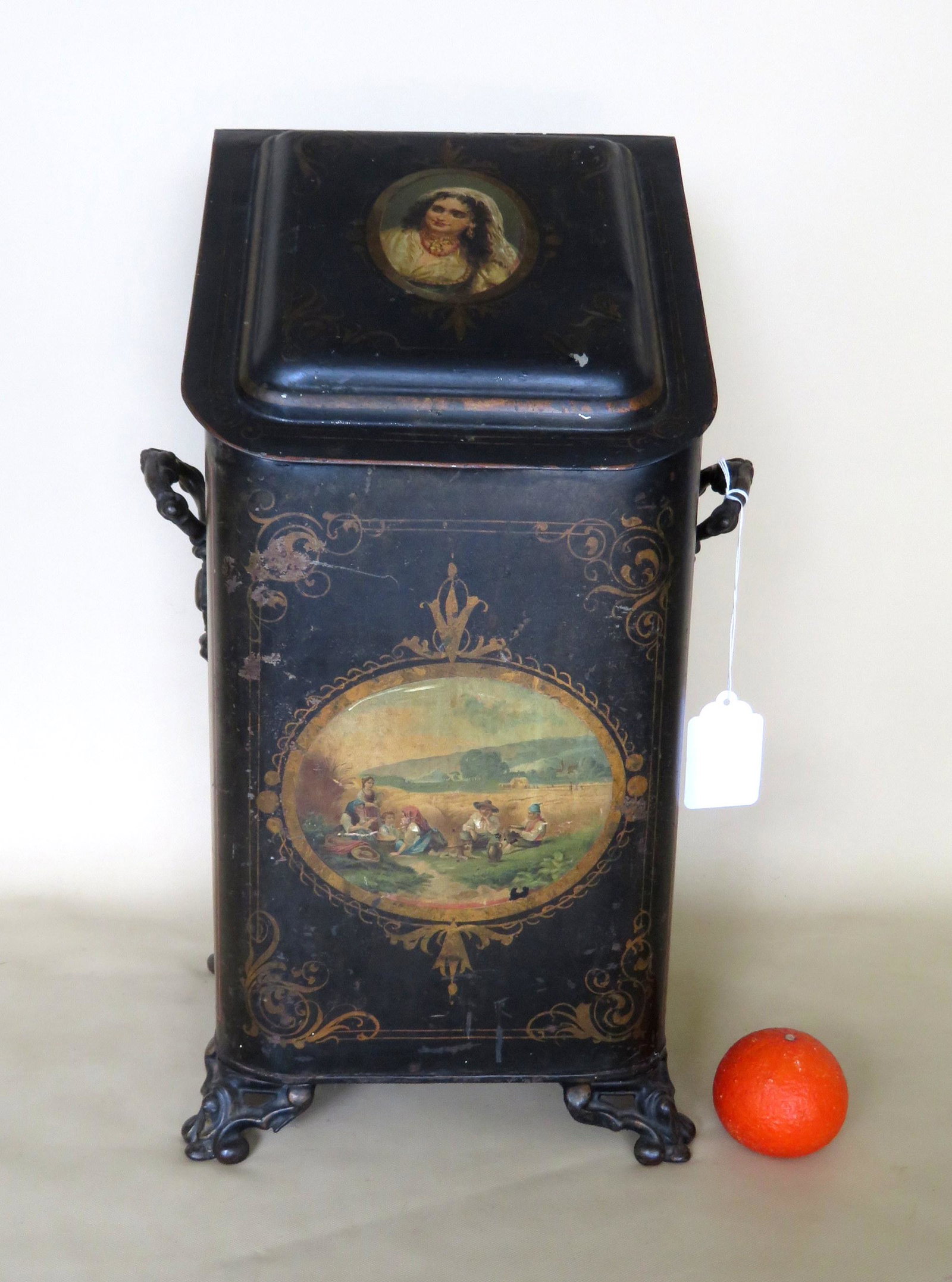 A hand painted toleware coal bin with insert. The lid: A hand painted toleware coal bin with insert. The lid decorated with a portrait of a gypsy woman, and the front panel with a scene of peasant farmers with family, 19th century. Very good original cond