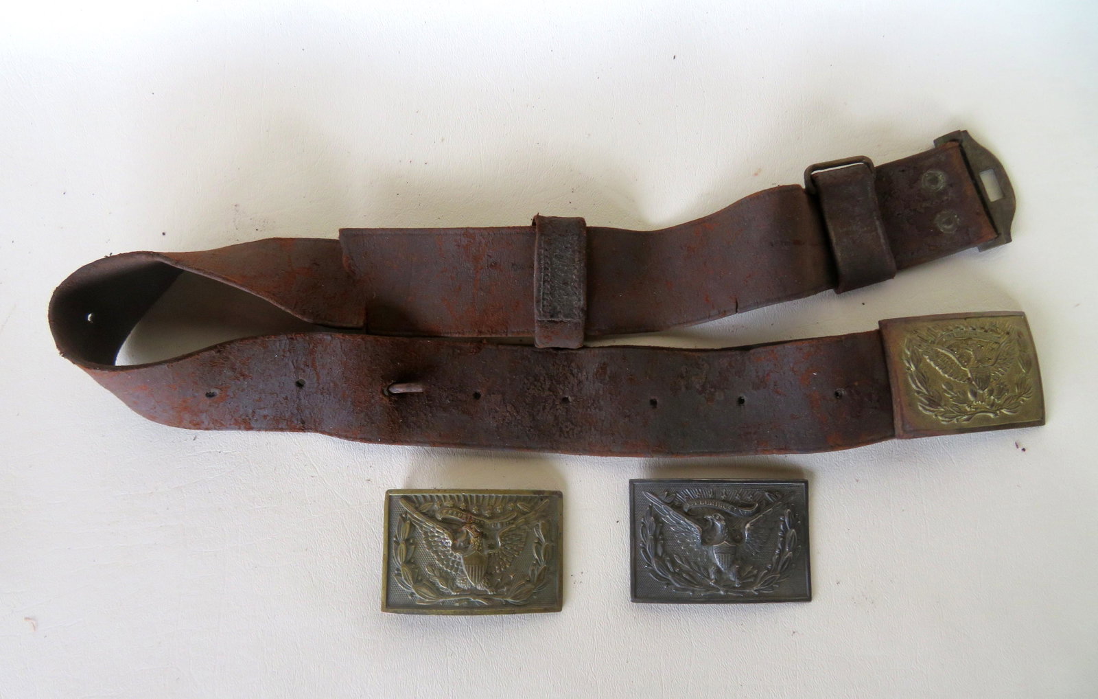 Three Indian Wars 1874 belt buckles and 1 leather belt: Three Indian Wars 1874 belt buckles and 1 leather belt with knife holding hook. Includes 2 in brass and 1 in silver plate. The buckles all in good condition. The belt with tear and use wear and in fai