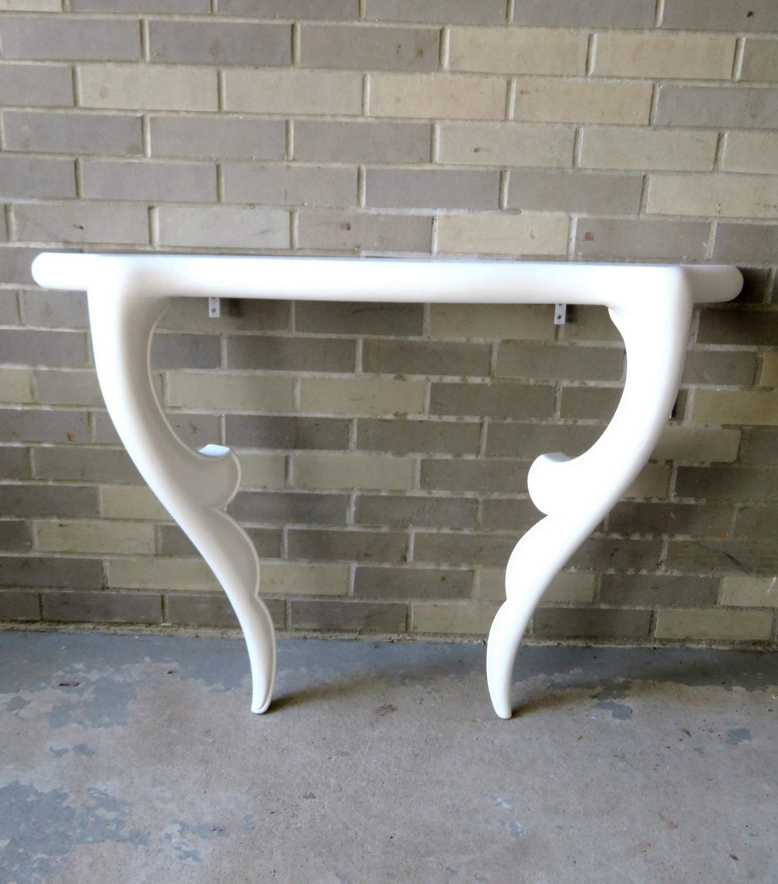 A mid-century Hollywood Regency style wall mounted: A mid-century Hollywood Regency style wall mounted console table, professionally restored in newer white paint. Very good condition. 42"W x 11"D x 30 1/4"H.