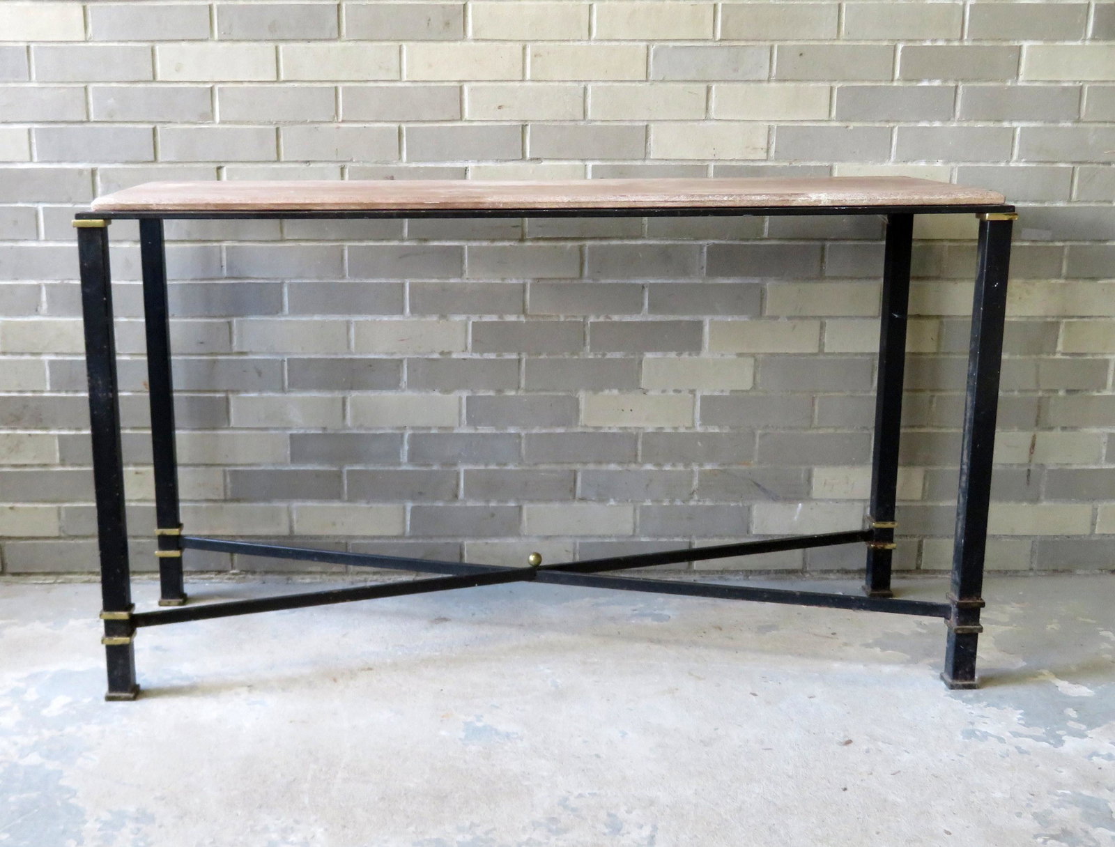 A continental style iron porch sofa table or plant: A continental style iron porch sofa table or plant table with brass highlights, and having what appears to be a semi-porous stone top, and cross stretchers in original black paint. Circa 1950-70. Some