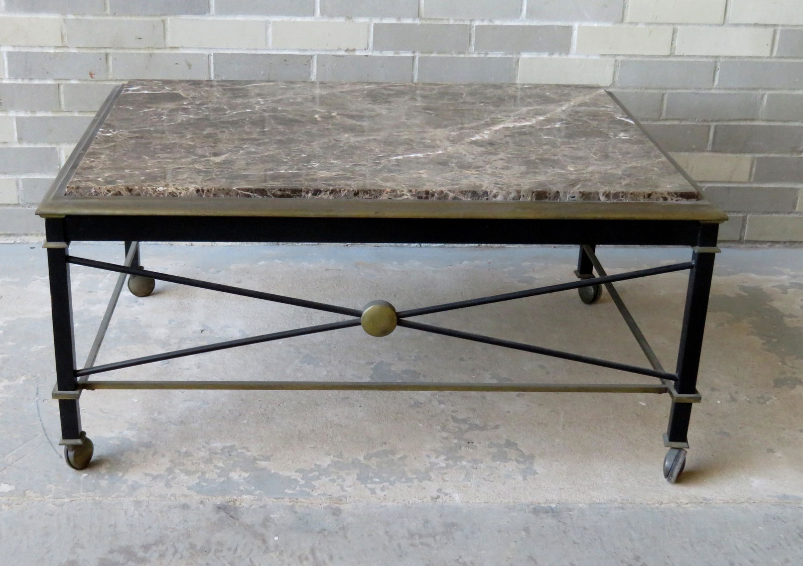 Mid-century Italian style marble top coffee table with: Mid-century Italian style marble top coffee table with brass plated shaped frame and original black paint on legs and cross stretchers, mounted on wheels, circa 1950-70, very good condition. 29" x 37"