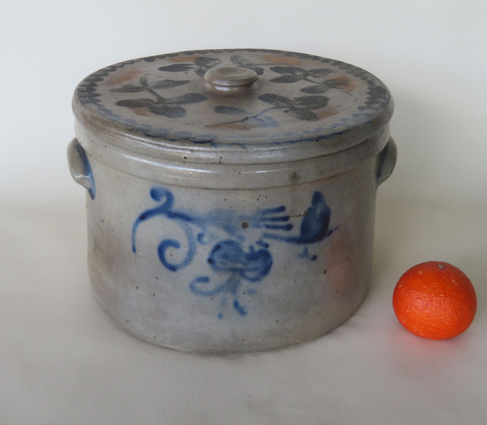 Stoneware butter crock with decorated lid. The 3 gallon: Stoneware butter crock with decorated lid. The 3 gallon crock with near matching blue flowers on stem on front and back, brushed blue ears, and the stoneware lid with a wavy line border surrounding 4