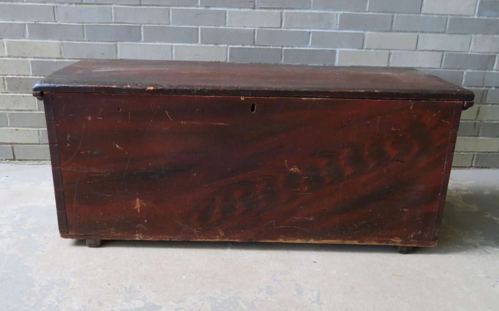 Two primitive painted blanket boxes. The first in red: Two primitive painted blanket boxes. The first in red and black grain paint with original feet and cleats to ends of lid - one hinge missing, the other with small repair and loose without screws, rose