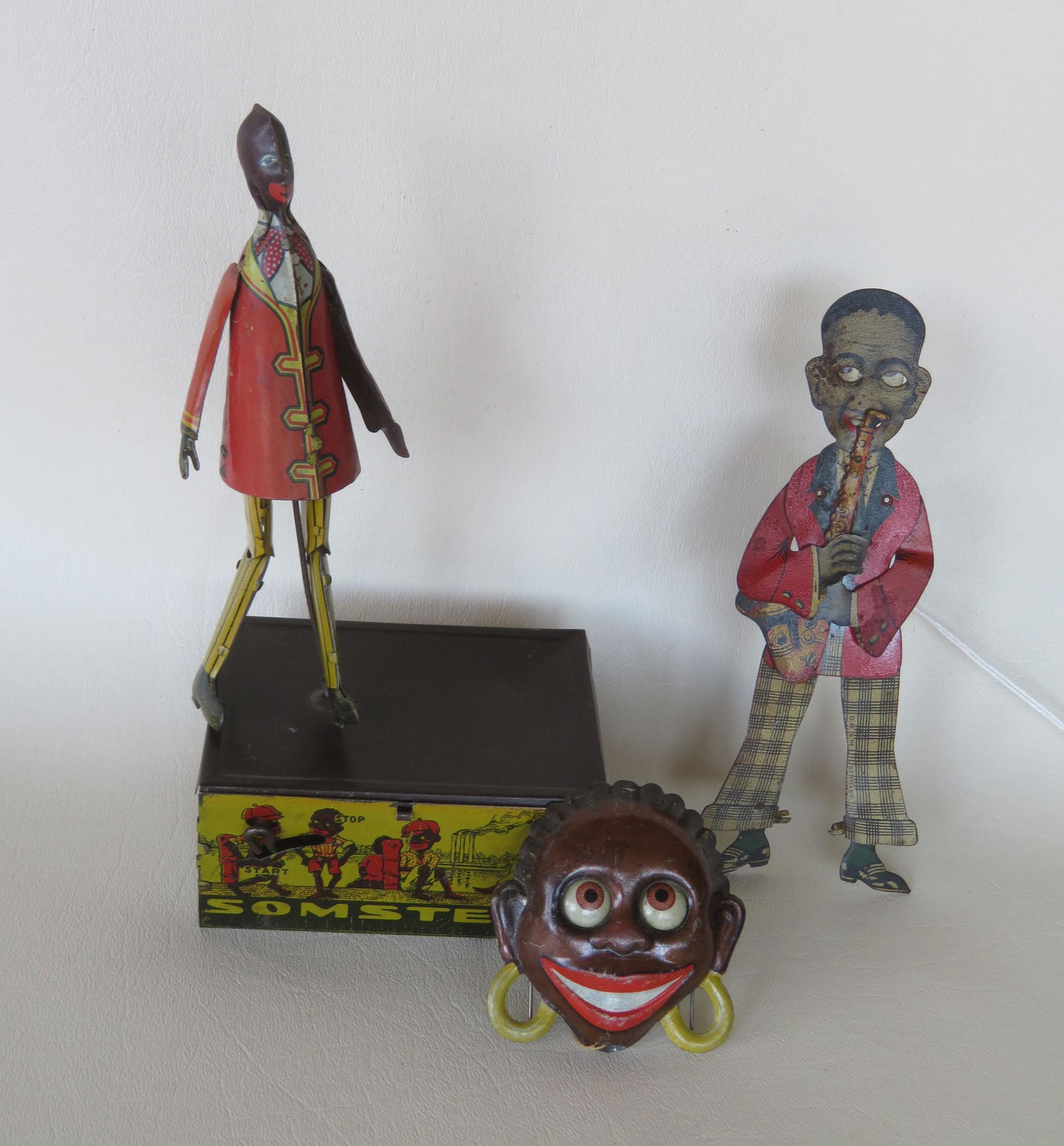 Three African American articulated tin toys including:: Three African American articulated tin toys including: A Marx tin lithograph windup "Somstepa Coon Jigger" dancing toy, early 20th century - condition: the 2 tabs that hold the top of the dancing plat