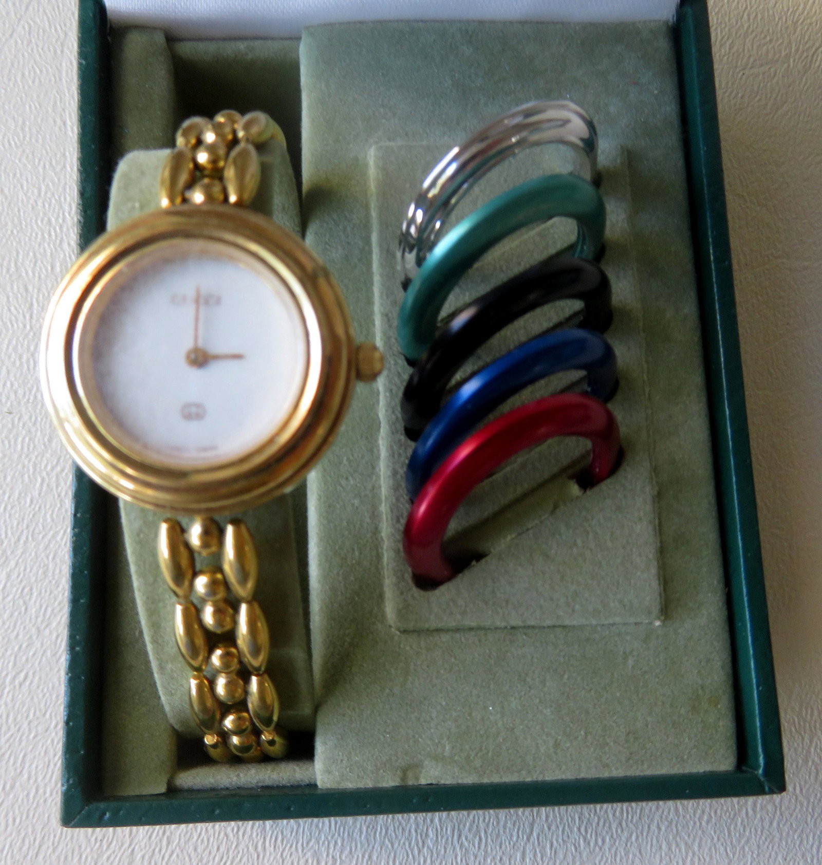 Gucci gold plated wrist watch marked on bottom of case: Gucci gold plated wrist watch marked on bottom of case "Gucci 11/12 0114017". Original box and papers with 5 extra colorful bezels. The crystal with extensive scratch marks but the watch is in good wo