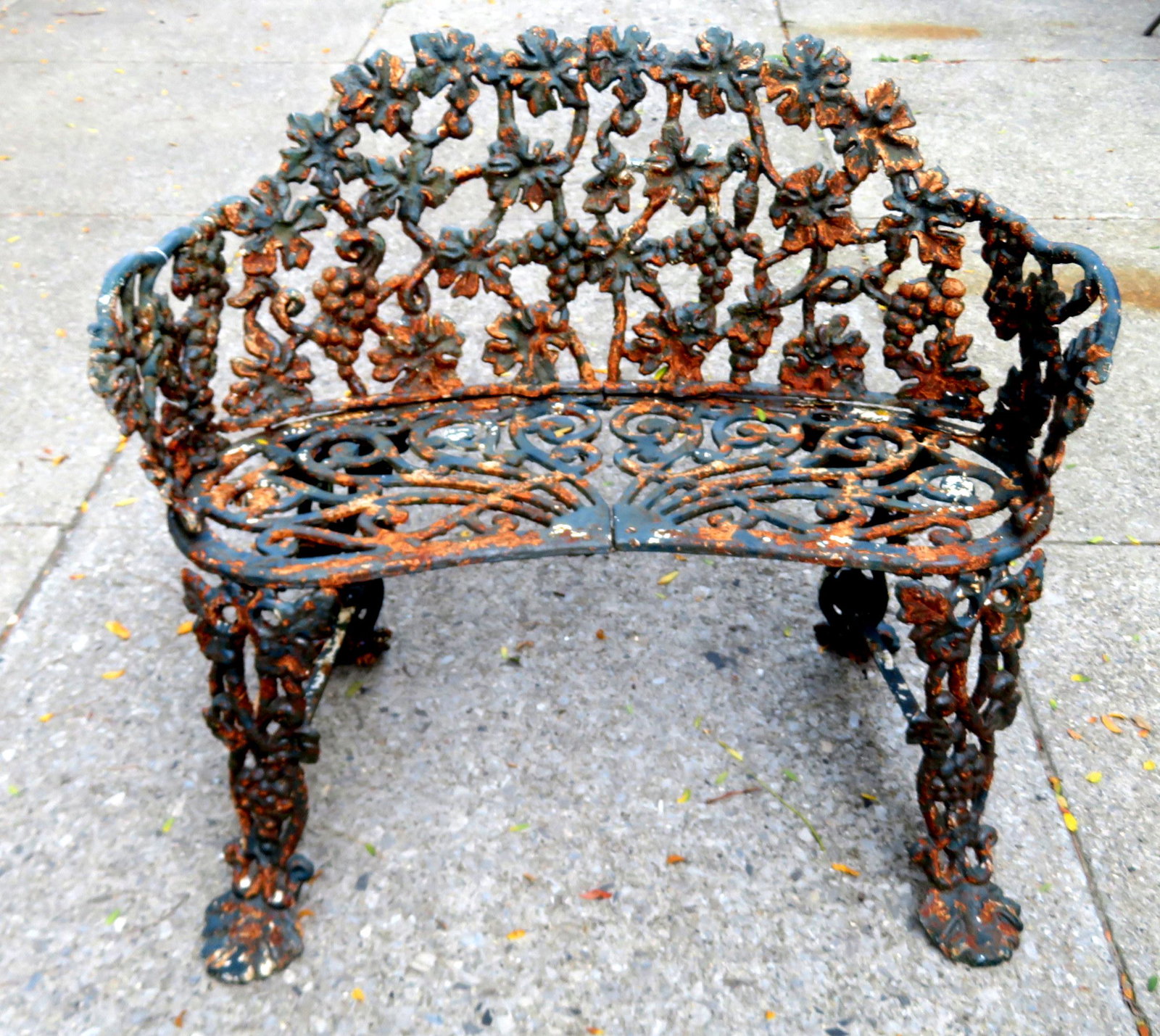 Good heavy cast iron garden settee in the grape and: Good heavy cast iron garden settee in the grape and vine pattern and having a fretwork scrolled seat. Early to mid 20th century. 34"W x 22"D x 28"H. Layers of old paint. Good condition.