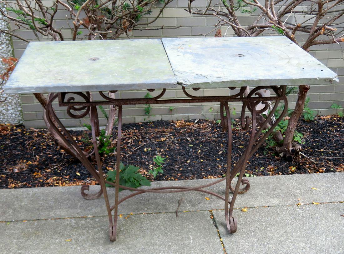 Hand made wrought iron console table with scrolled base: Hand made wrought iron console table with scrolled base and with a replaced top consisting of 2 square slate panels. Each panel with a small central hole surrounded by incised concentric circles. The 