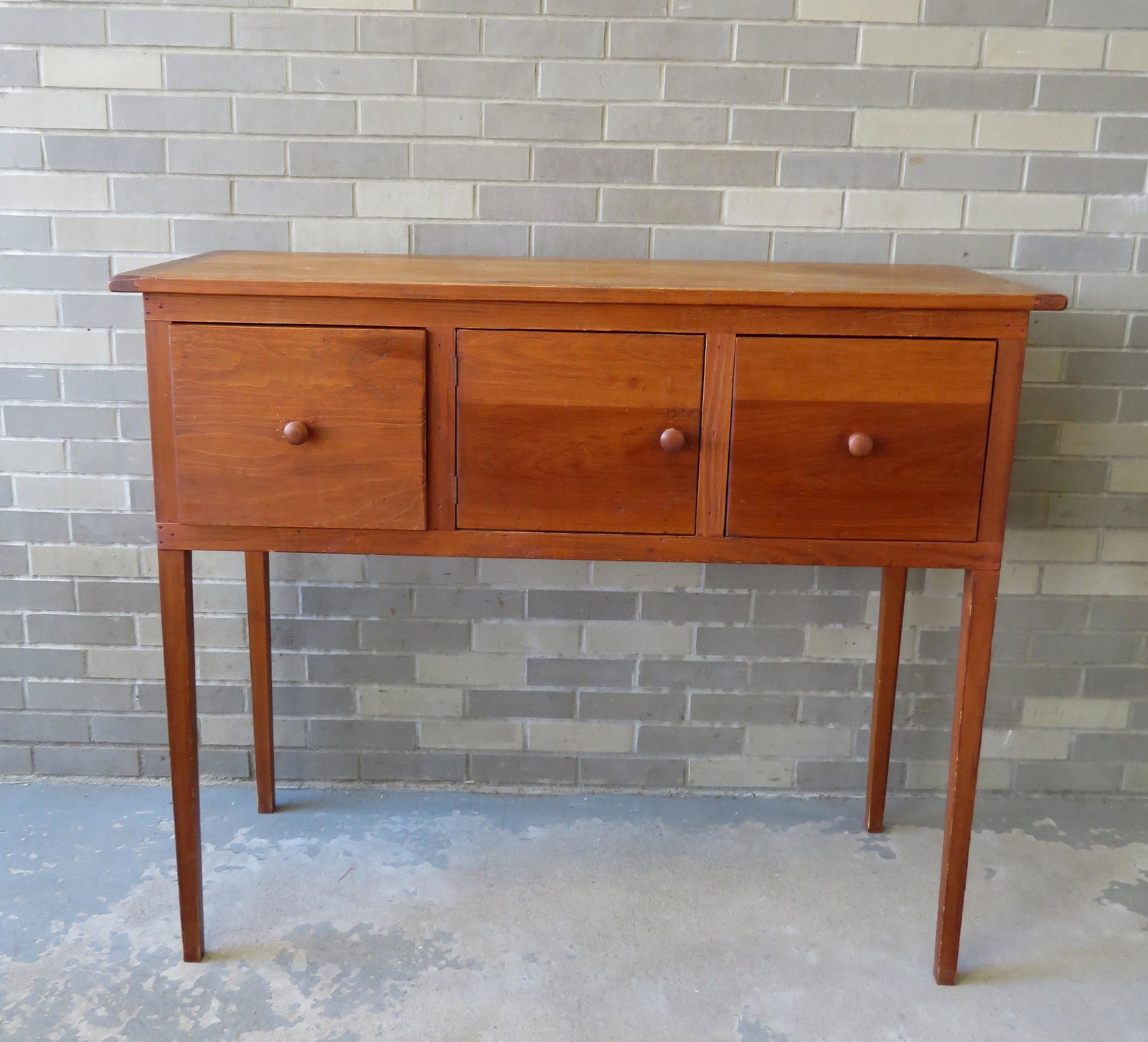 A Hepplewhite style custom made pine sideboard by: A Hepplewhite style custom made pine sideboard by Ingersoll Cabinet Makers (West Cornwall CT). Minor use wear, expansion crack on top board, but overall very good condition. Size 49"W x 19 1/4"D x 41 