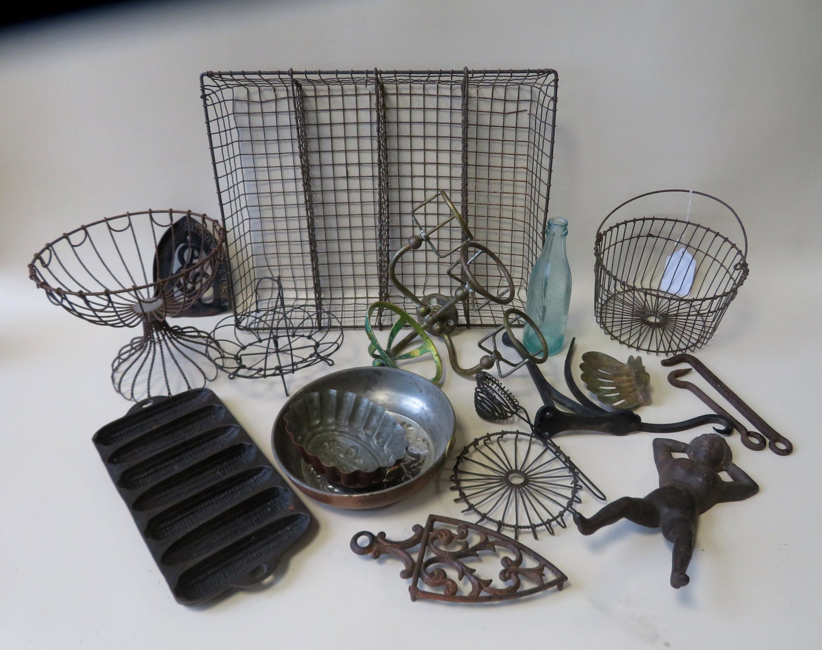 Grouping of mostly 19th century country metal work: Grouping of mostly 19th century country metal work collectibles including: Wire baskets, bathroom soap and glass holder, copper molds, 2 iron trivets, and a cast iron Wagner corn mold. All items in ve