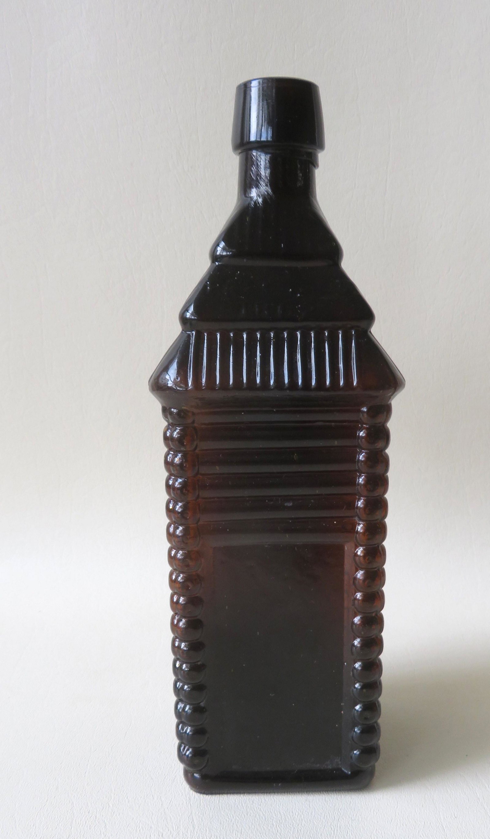 A signed "S.T. DRAKE: A signed "S.T. DRAKE'S 1860 PLANTATION BITTERS" bottle, cabin form, reverse side embossed "PATENTED / 1862", applied sloping spout, plain hinge mold base, deep amber. 10" H. Very good condition with n